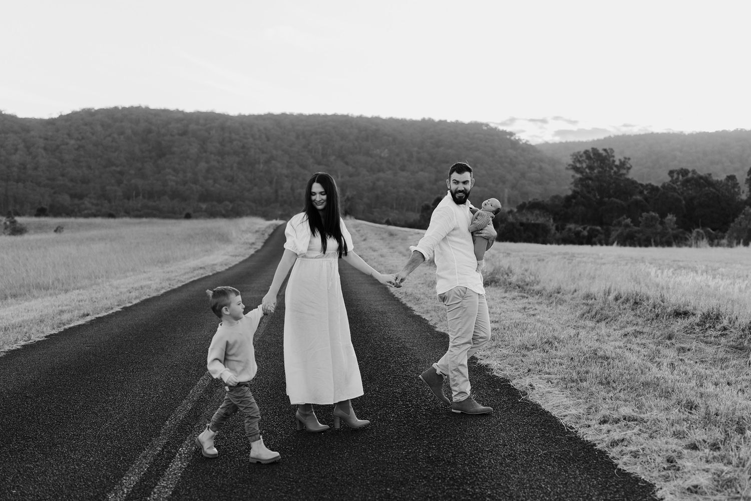 Family holding hands crossing country road in Castlereagh
