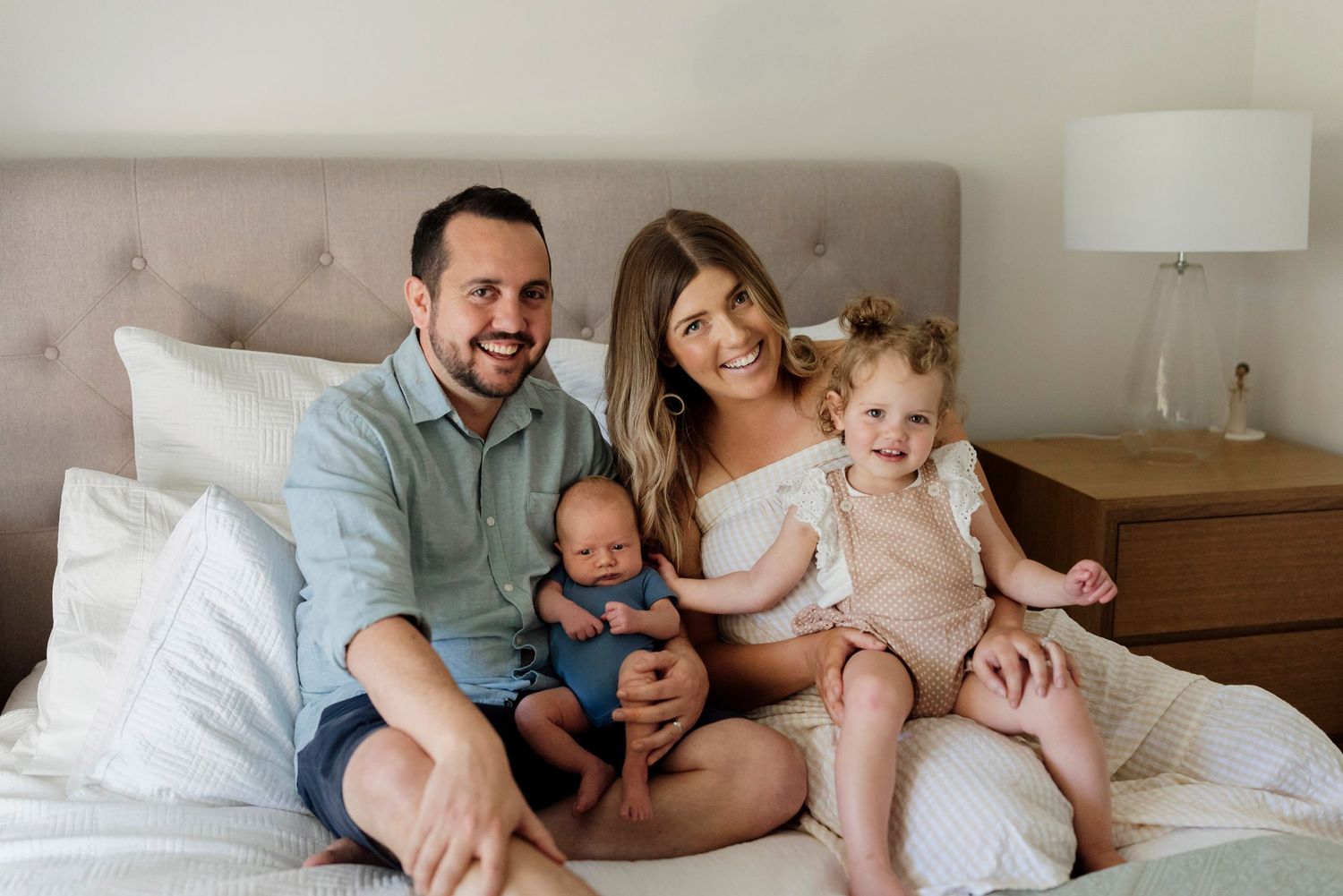 Family sitting on the bed looking at the camera during a newborn home session