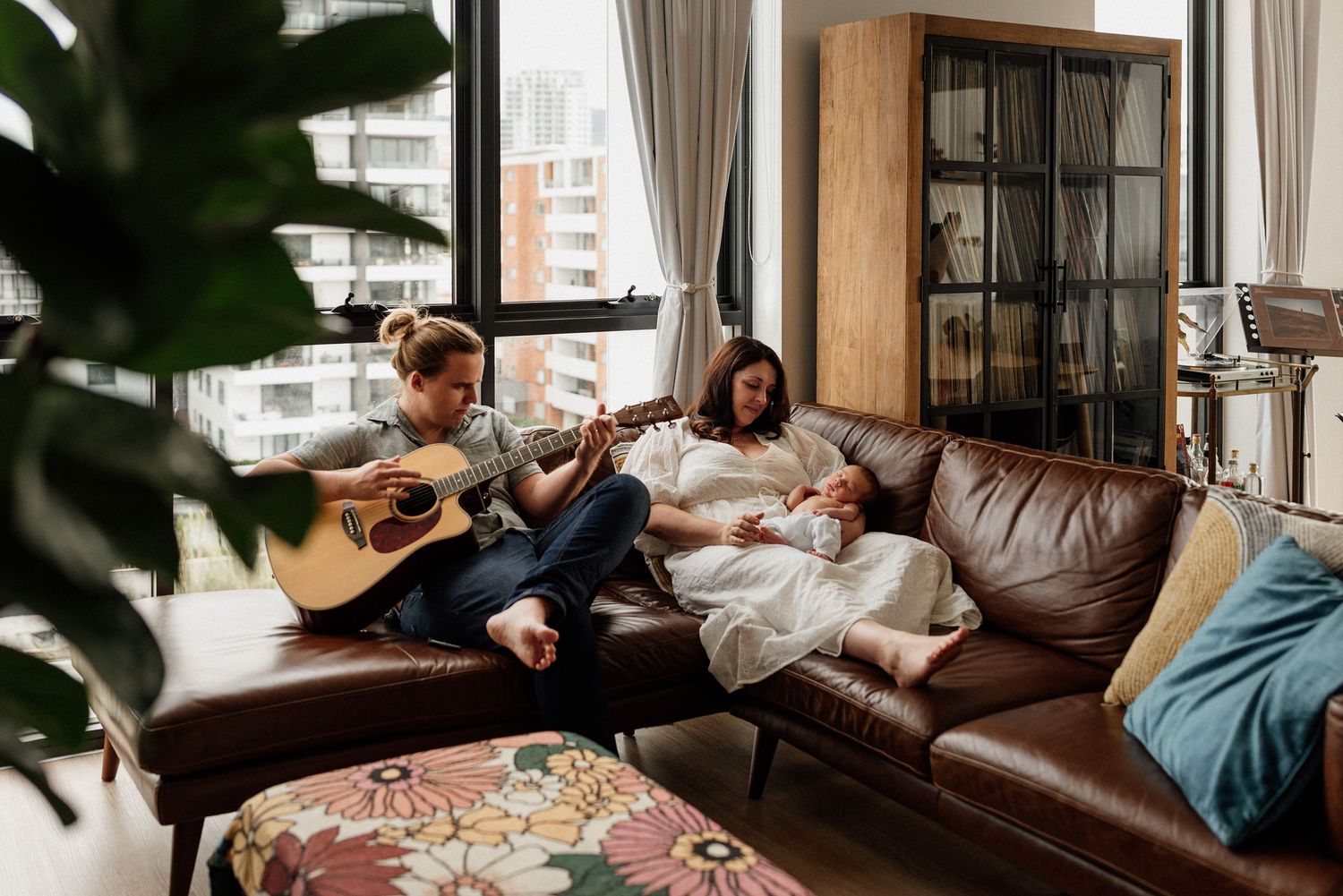 Father playing guitar to mother and sleeping baby during in-home photoshoot
