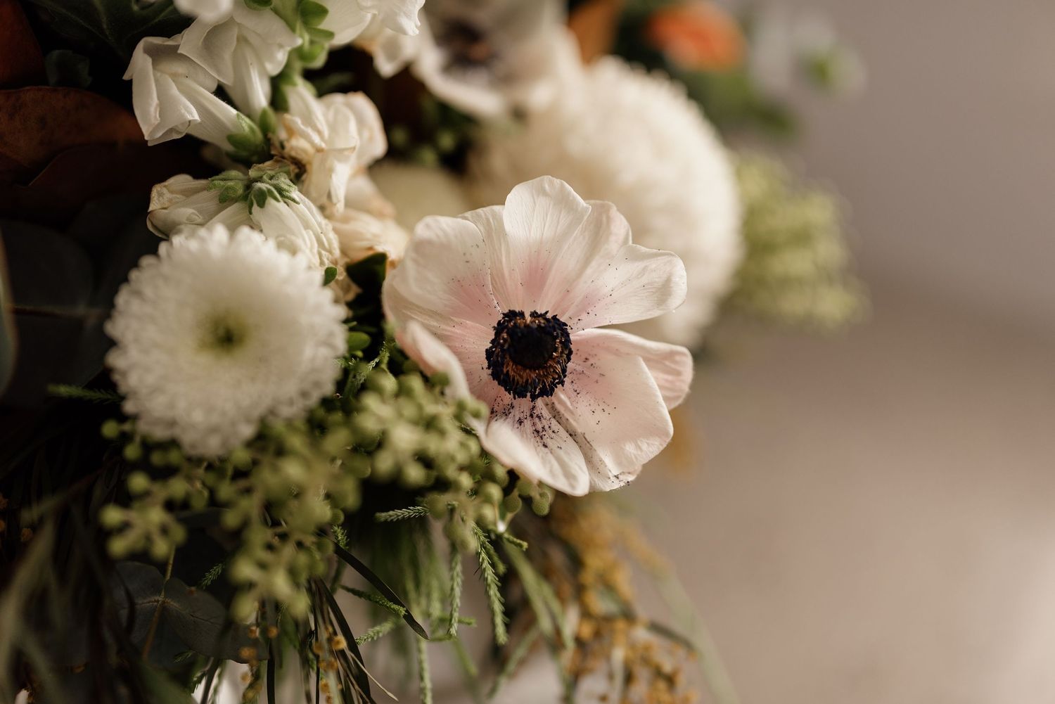 Beautiful white anemone and chrysanthemum wedding bouquet with lush greenery.