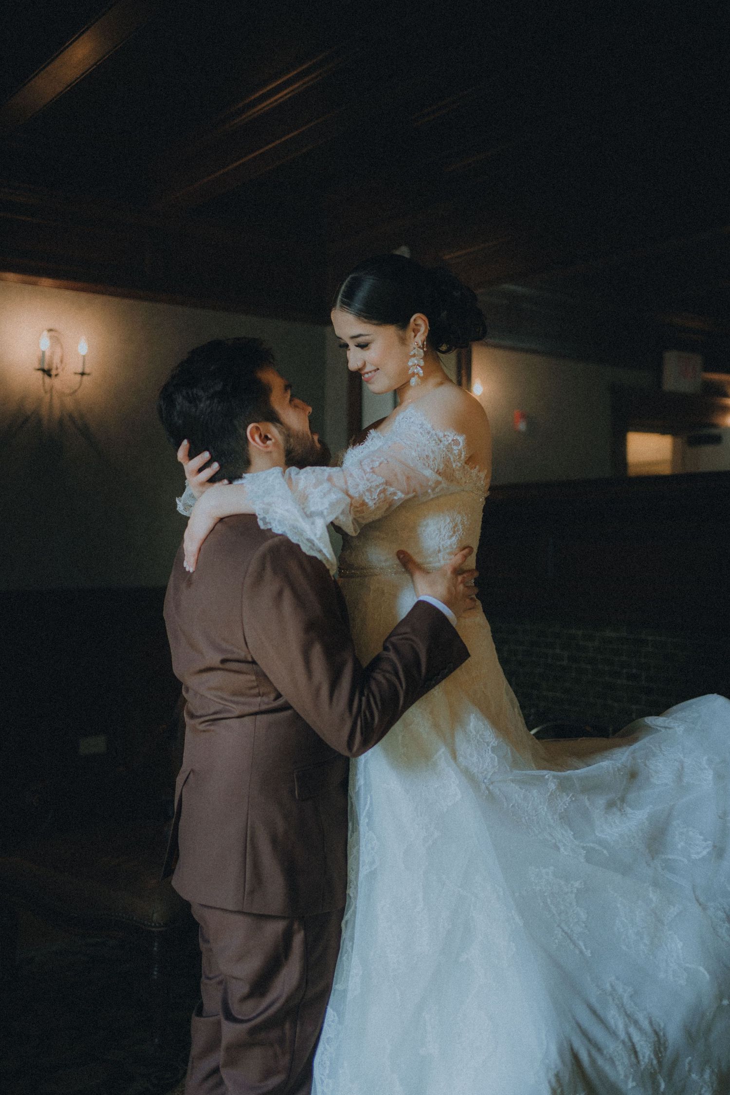 A couple in wedding attire share an intimate dance together in a dimly lit venue.