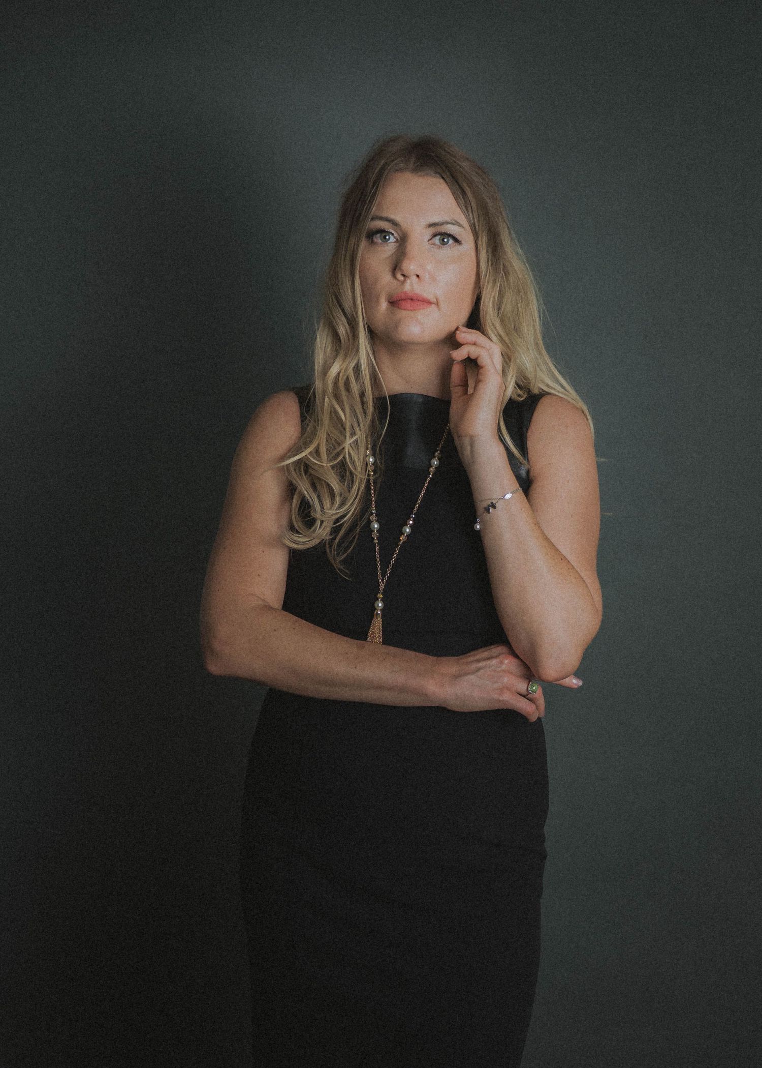 A moody series of portraits showing someone in a sleeveless black top against a dark background with dramatic lighting.