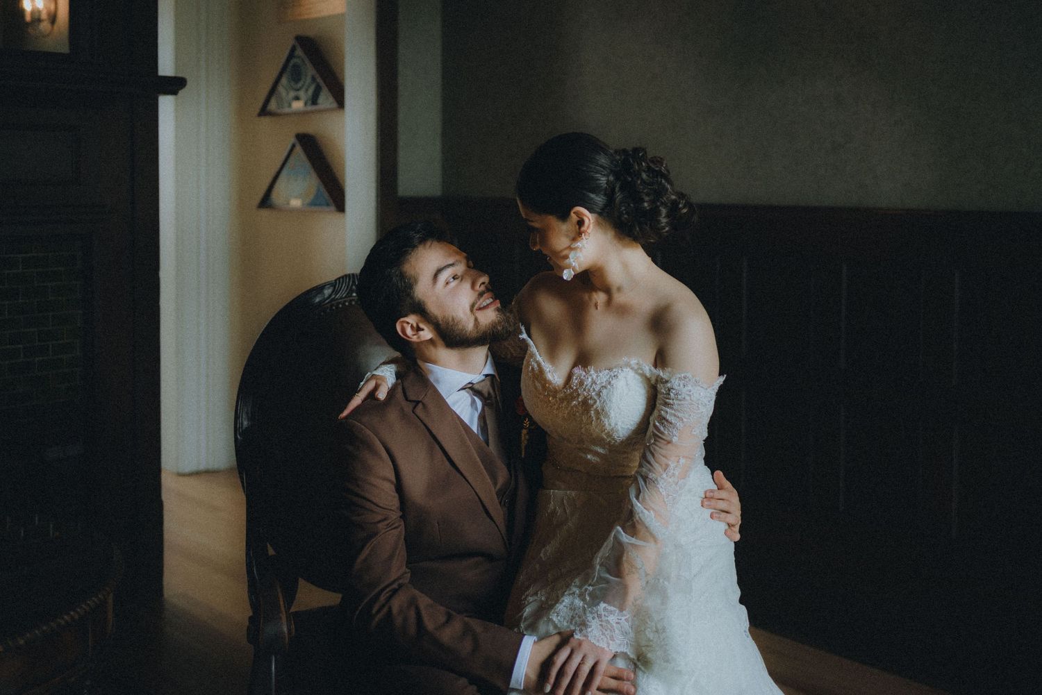 Romantic couple in wedding attire sharing intimate moments in a dimly lit indoor setting.