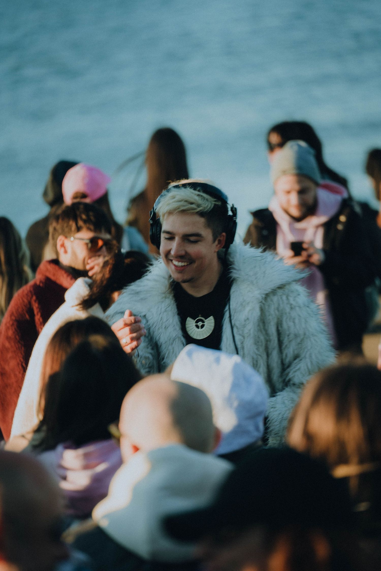 Group of people gathered outdoors for social event at sunset with blurred background and warm lighting.