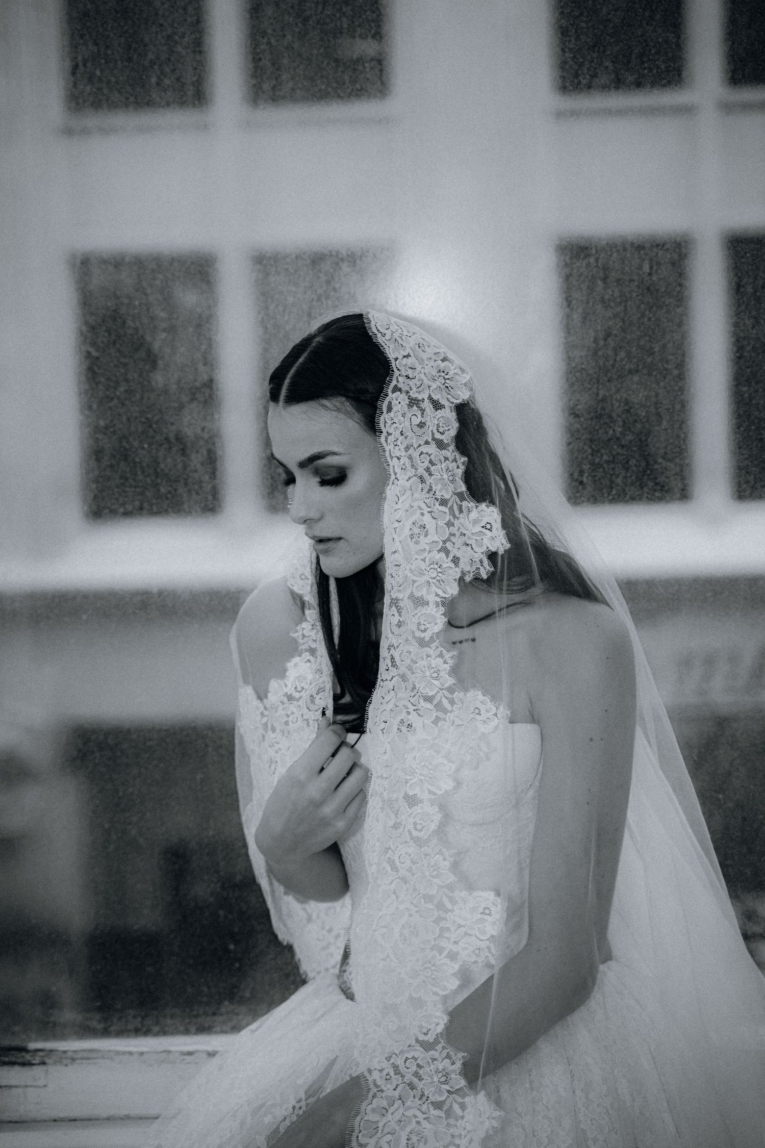 Elegant black and white bridal portrait featuring a delicate lace veil and strapless wedding gown in soft focus.