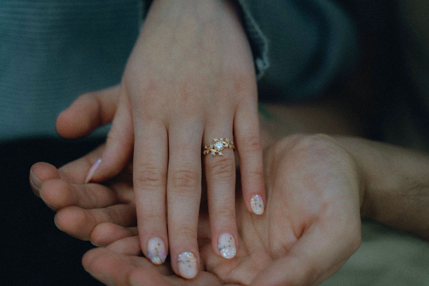 Close up view of an engagement ring and wedding band on a hand showing off the sparkling diamond details.