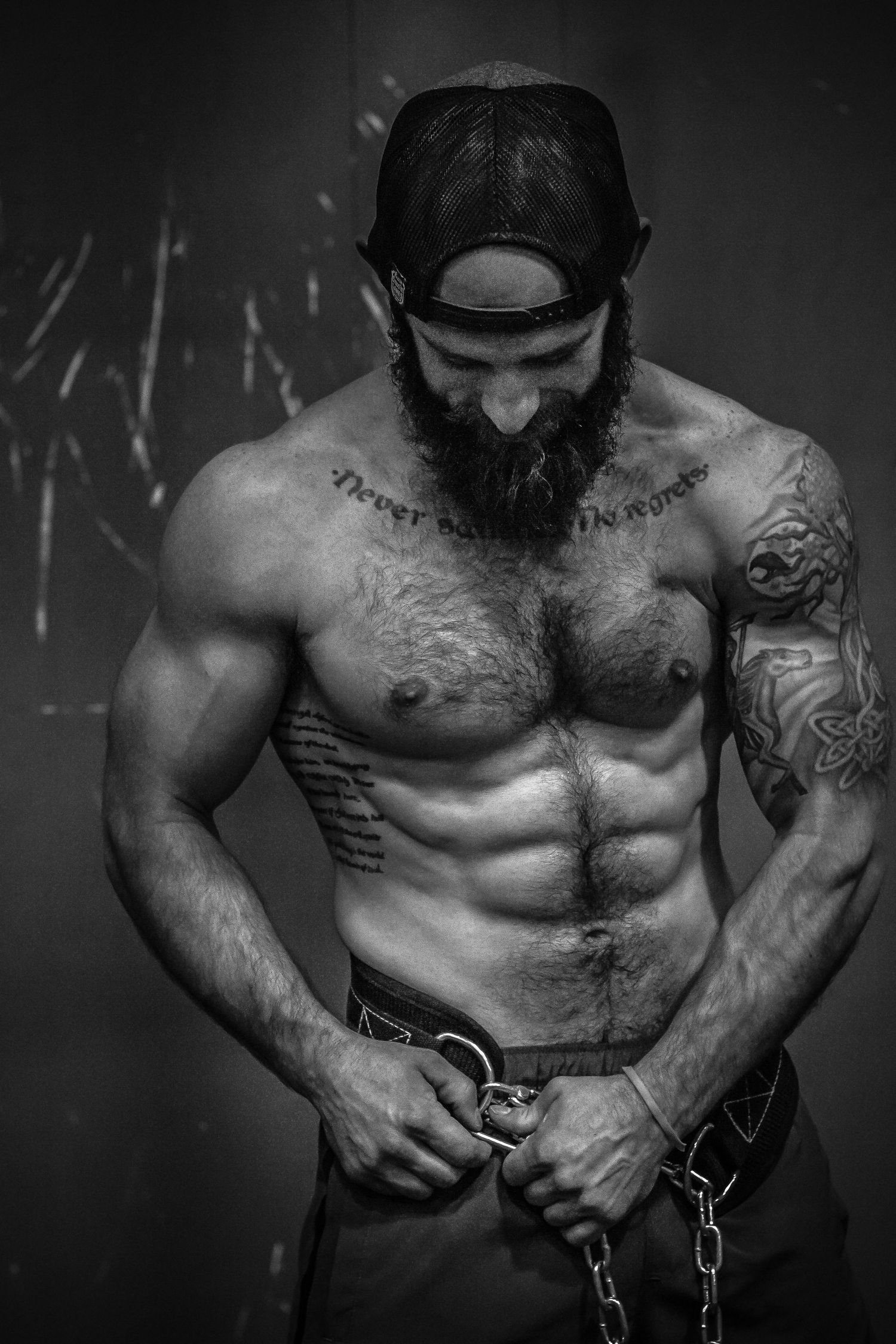 Black and white artistic sequence showing a muscular tattooed torso breaking free from chains in a dramatic studio setting.