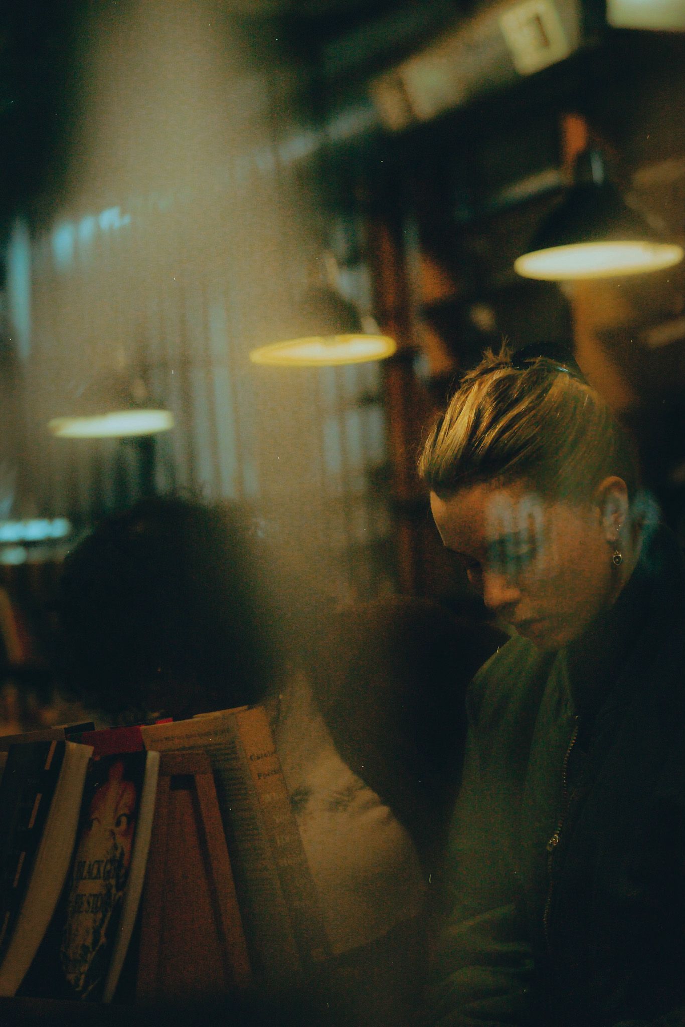 Moody nighttime scene in a dimly lit bar or restaurant with warm ambient lighting casting shadows against a wall.