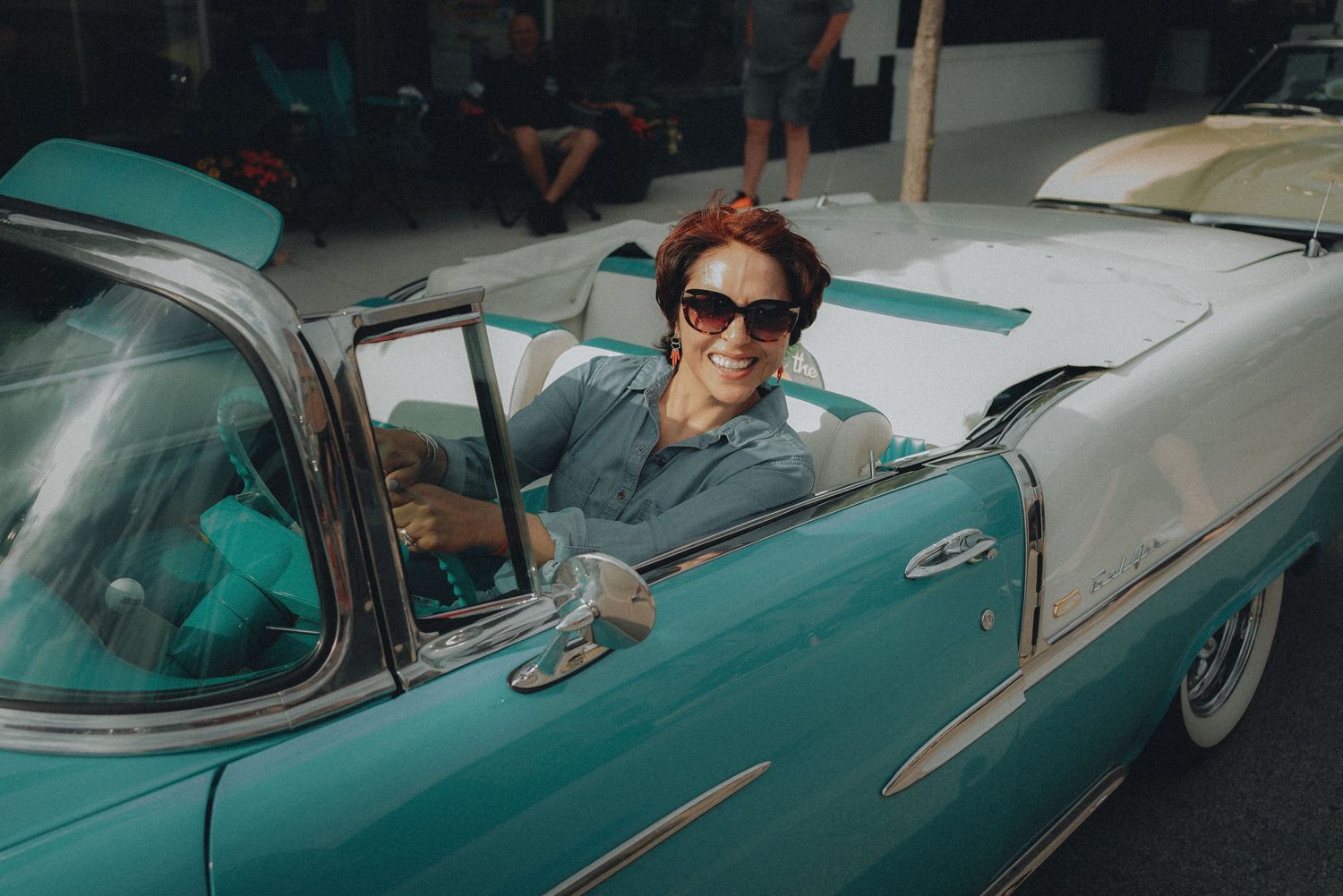 A vintage turquoise classic car with chrome trim parked on a street.