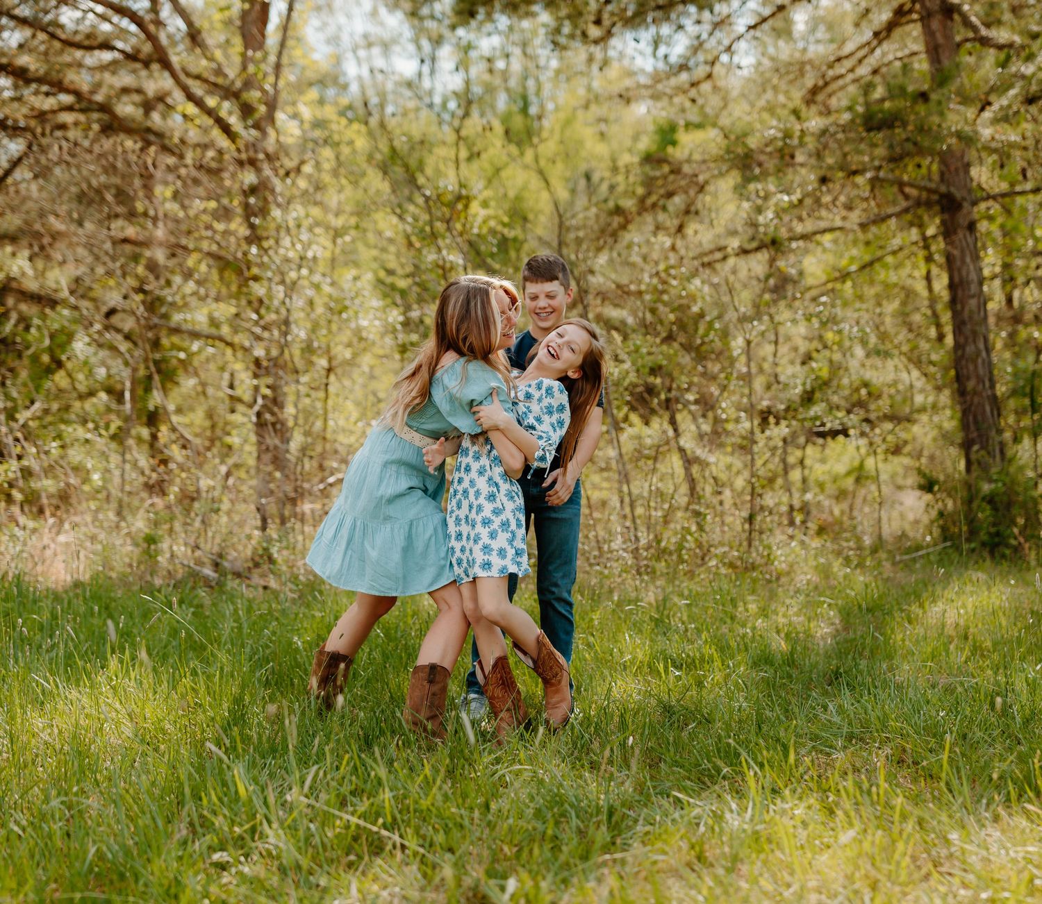 Family portrait session in a sunlit meadow with natural greenery and soft lighting.