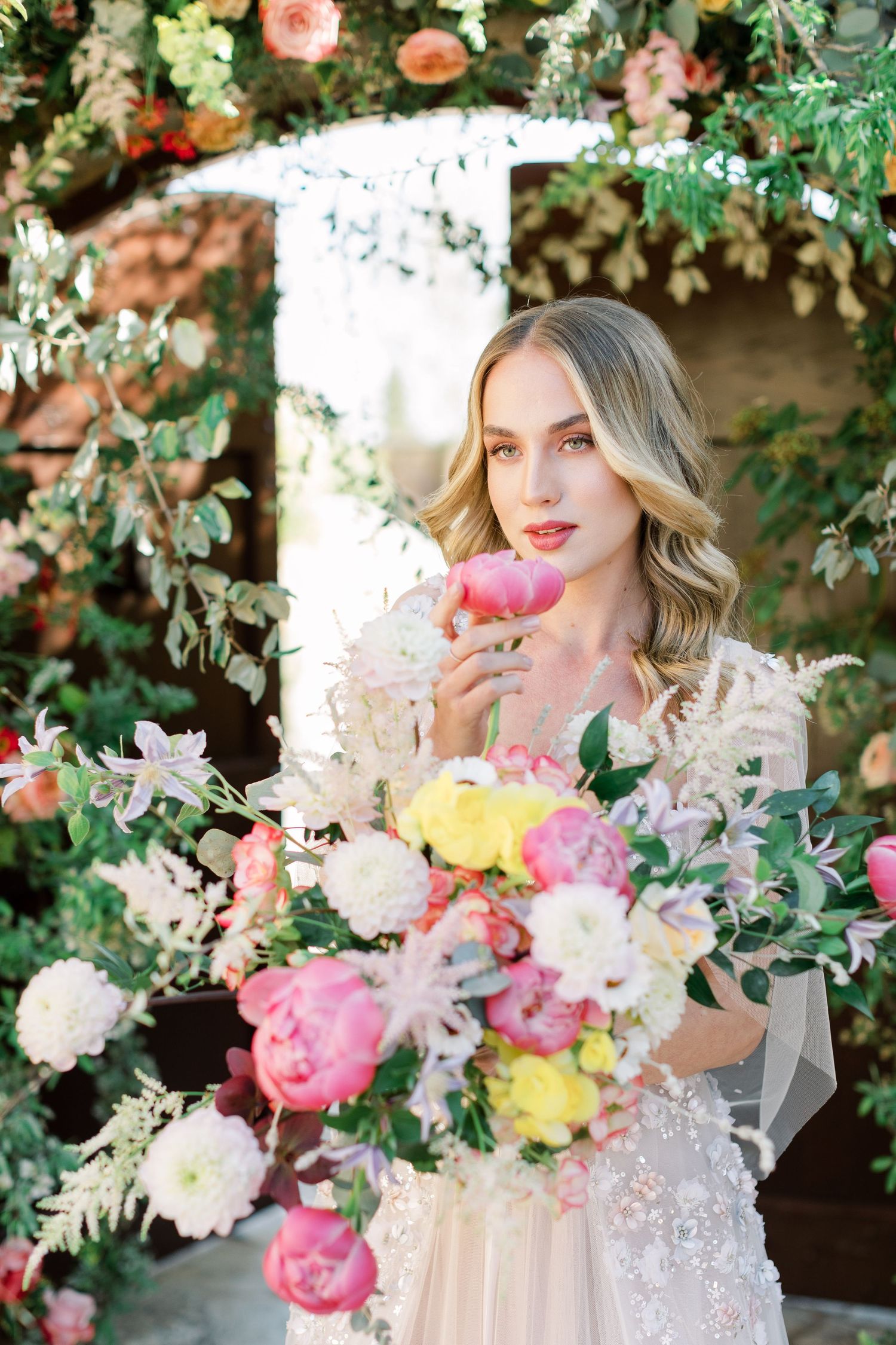 Romantic floral portrait with blush and yellow peonies, garden roses and delicate lace in an outdoor setting.