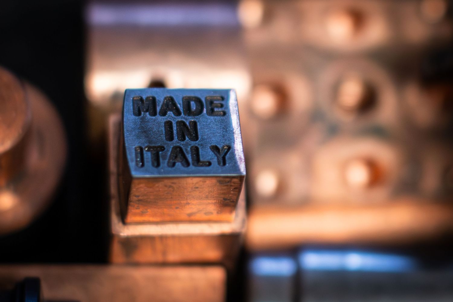 Close up macro shot of brass tooling showing 'Made in Italy’ lit in beautiful warm copper colours.