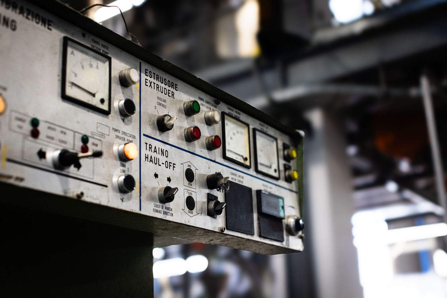 Italian heavy machinery control panel in HPDE pipe production factory with dark dramatic style and soft focus factory background.
