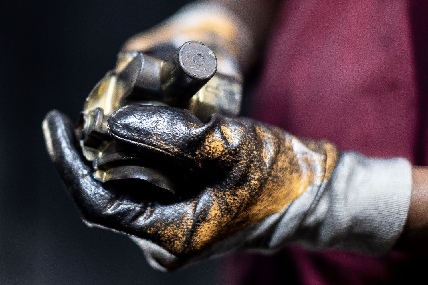 Close-up of hands with yellow PPE gloves darkened heavily with metal deposits.
