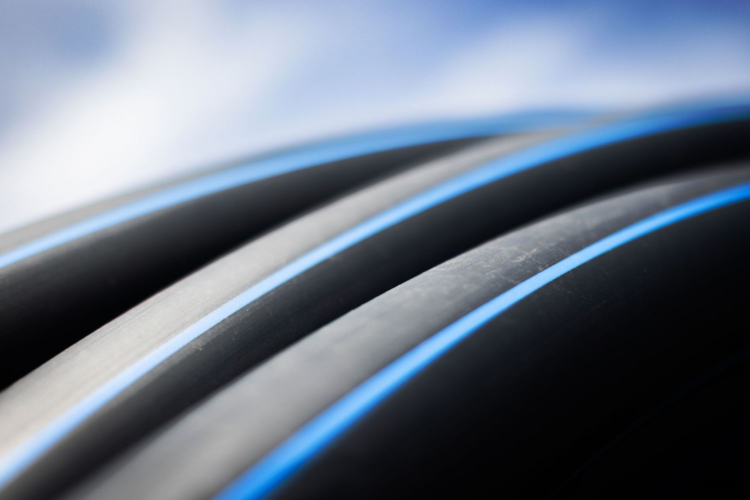 Abstract black HDPE piping with bright blue curved lines creating a sleek modern pattern against a sky background.