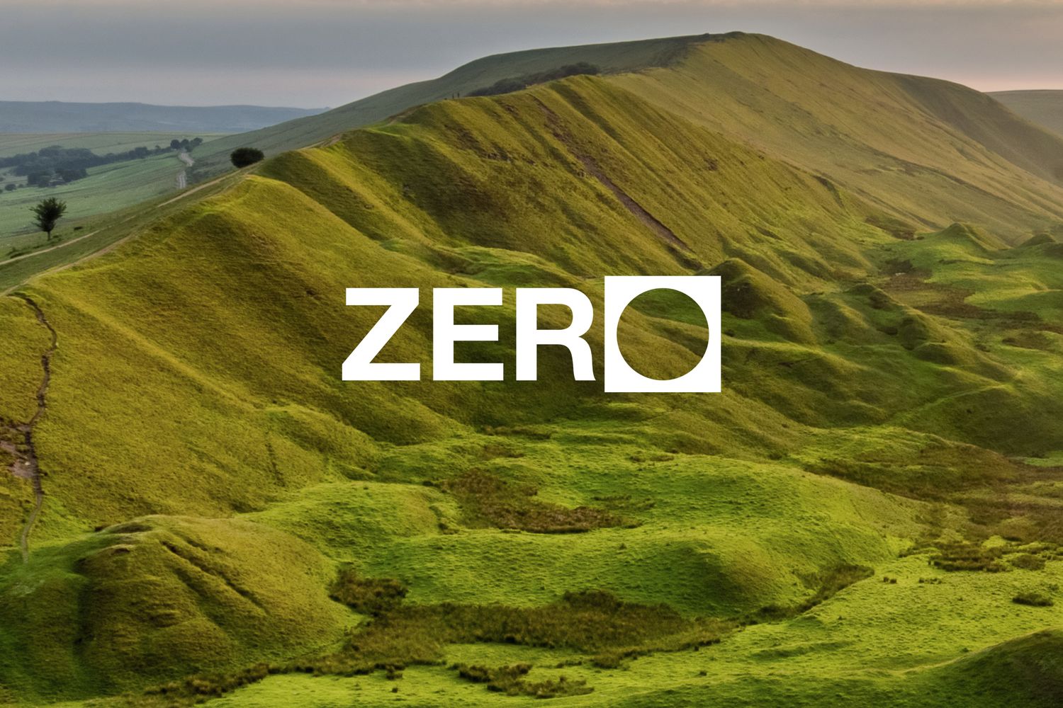 The word ZERO overlaid on a scenic green hillside landscape with rolling slopes under a cloudy sky.