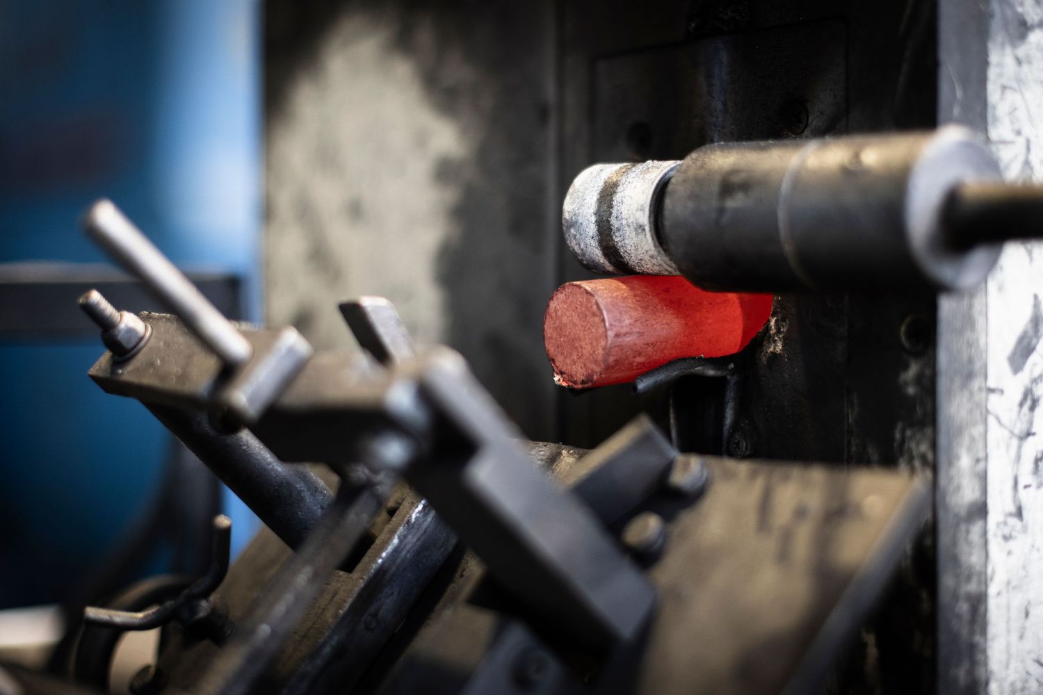 Close-up view of a red hot glowing steel cylinder transported by rolling machinery in production facility.