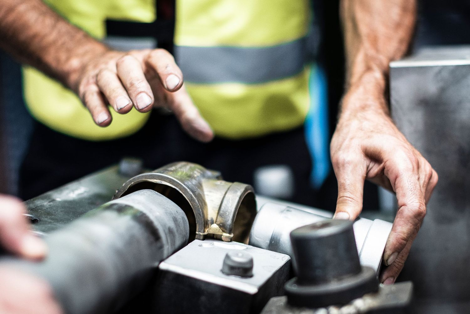 Close-up of factory worker hands and industrial tooling in an industrial manufacturing setting.