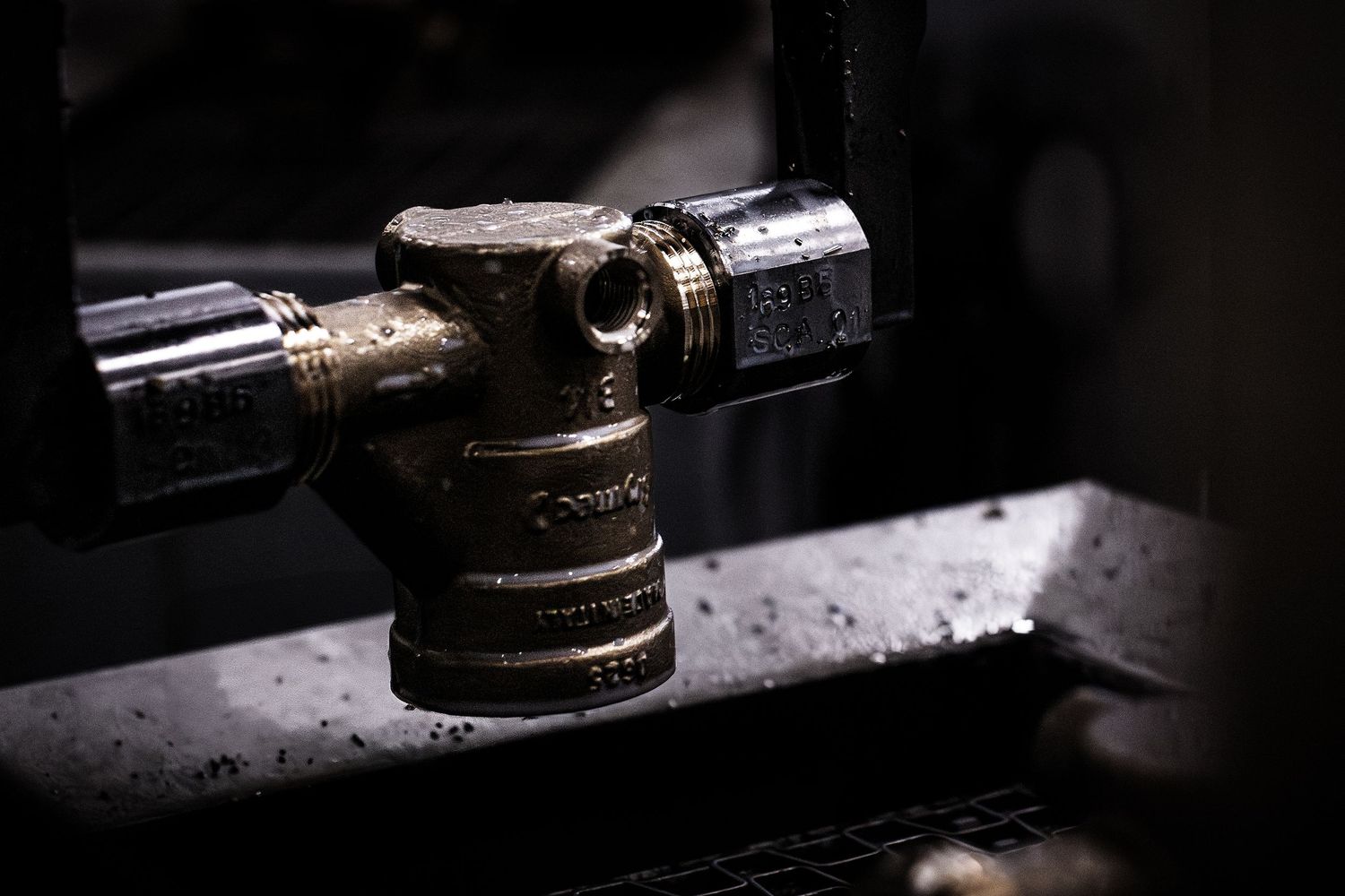 Close-up photograph of valve being moved by a robotic arm in dramatic low-key lighting.