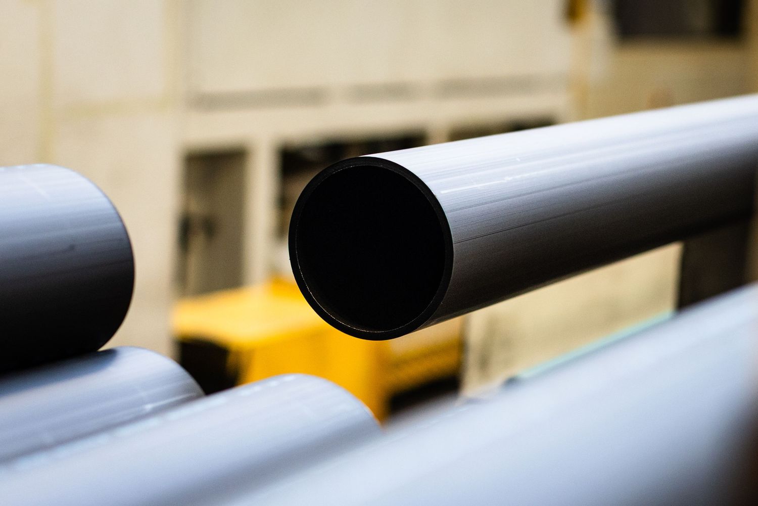 Close-up view of the open end of a black HDPE pipes in a pipe production factory.