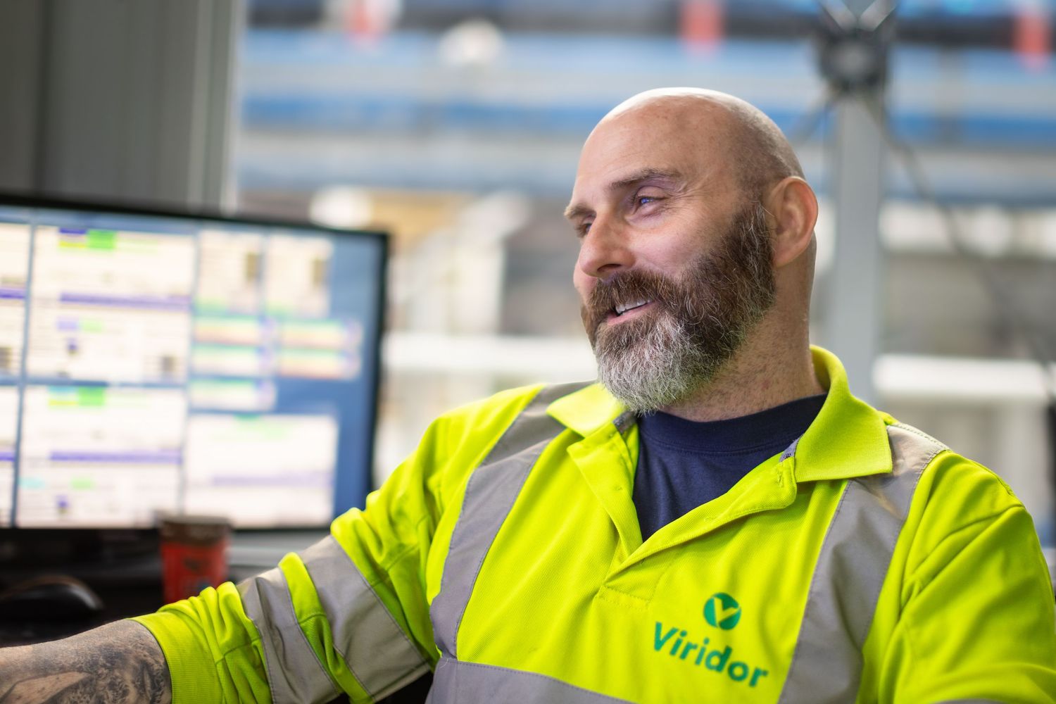 Worker in bright yellow safety vest operates equipment in industrial warehouse setting.