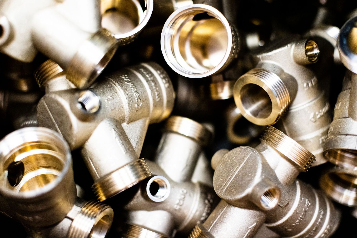 Close-up view of shiny brass plumbing fittings and pipe connectors arranged haphazardly.