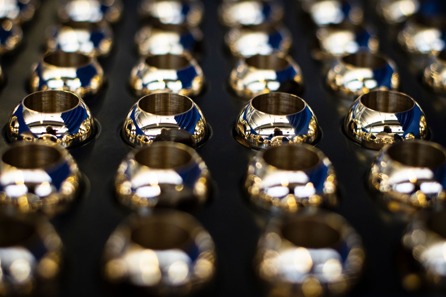 Close-up photography of highly polished brass valve components with sparkles and reflections on dark background.