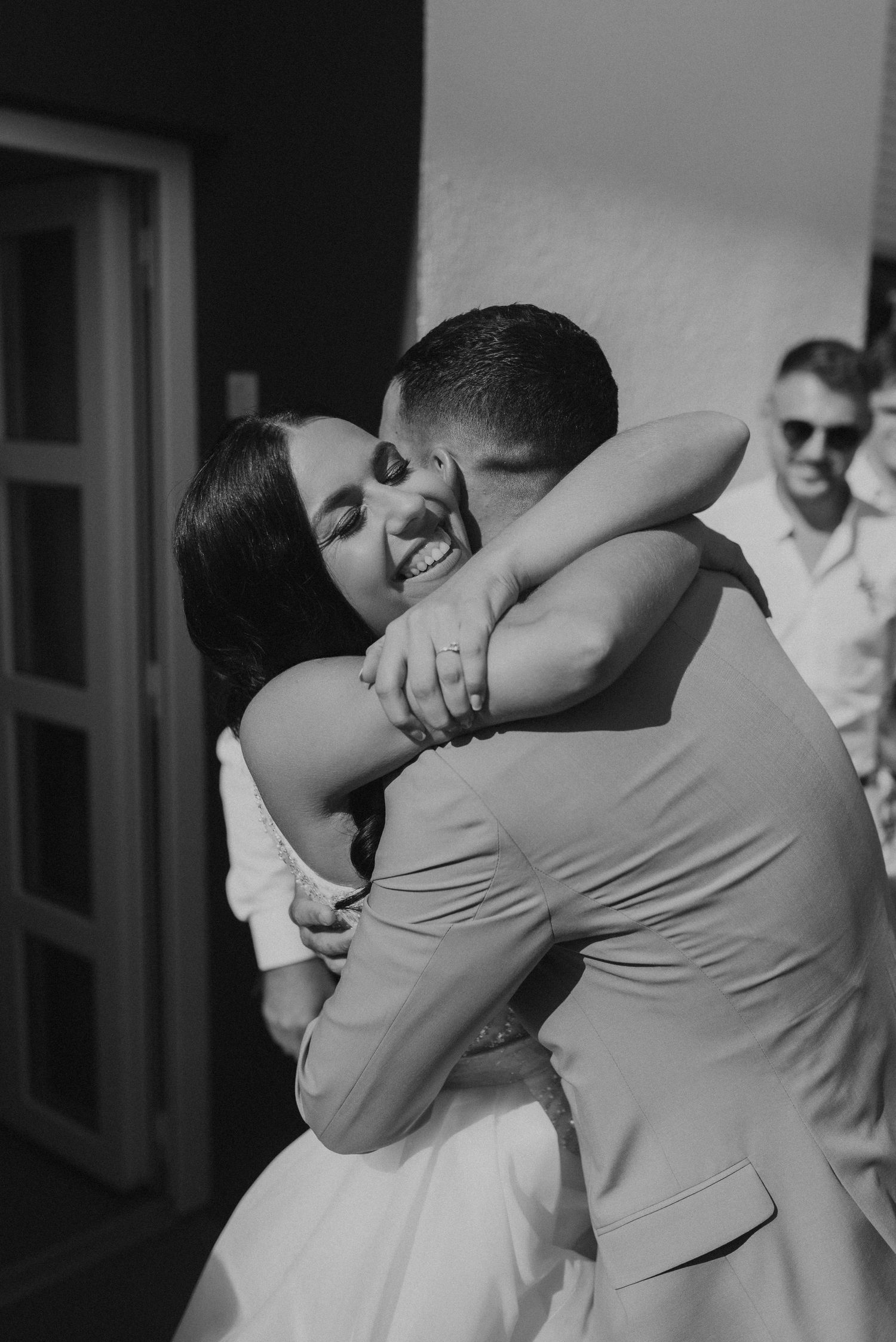 Intimate black and white wedding moment showing emotional embrace between newlyweds.