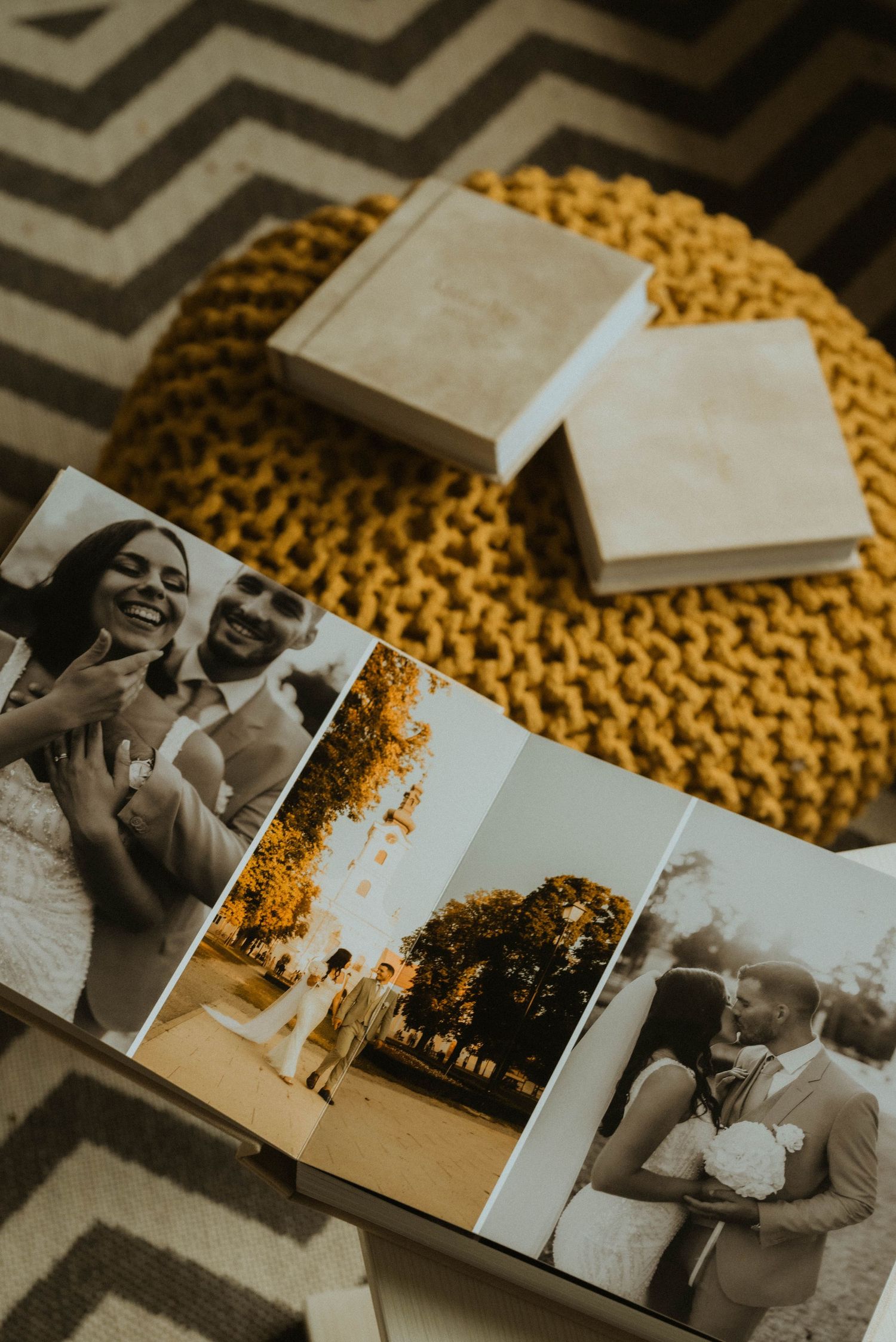 A vintage black and white wedding photo album displayed on a yellow knitted surface with chevron pattern in background.