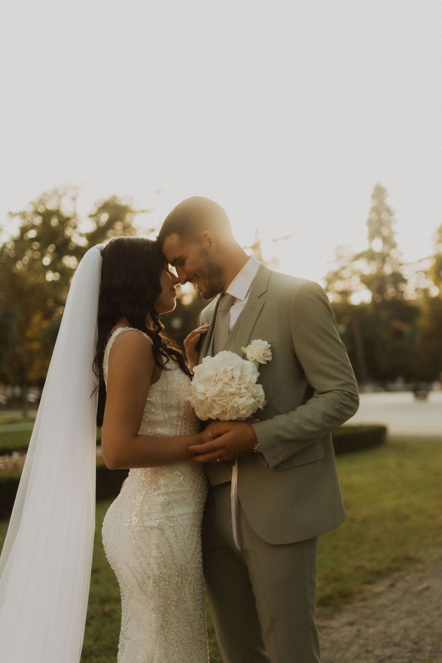 Romantic couple in wedding attire sharing intimate moment during golden hour sunset.