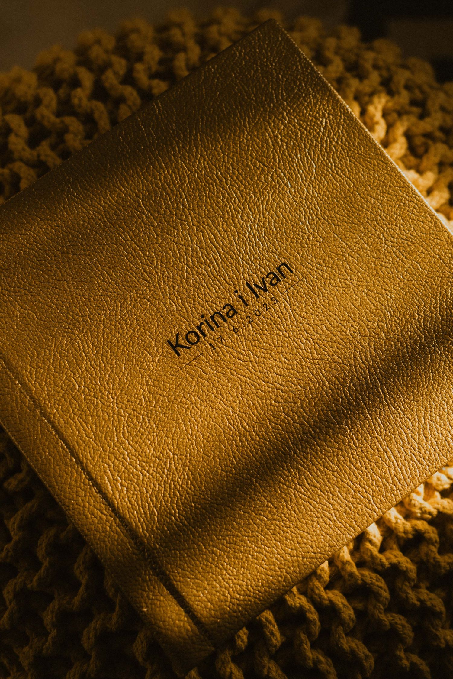 Brown leather photo album titled 'Katrina Ivan' on textured knit surface.