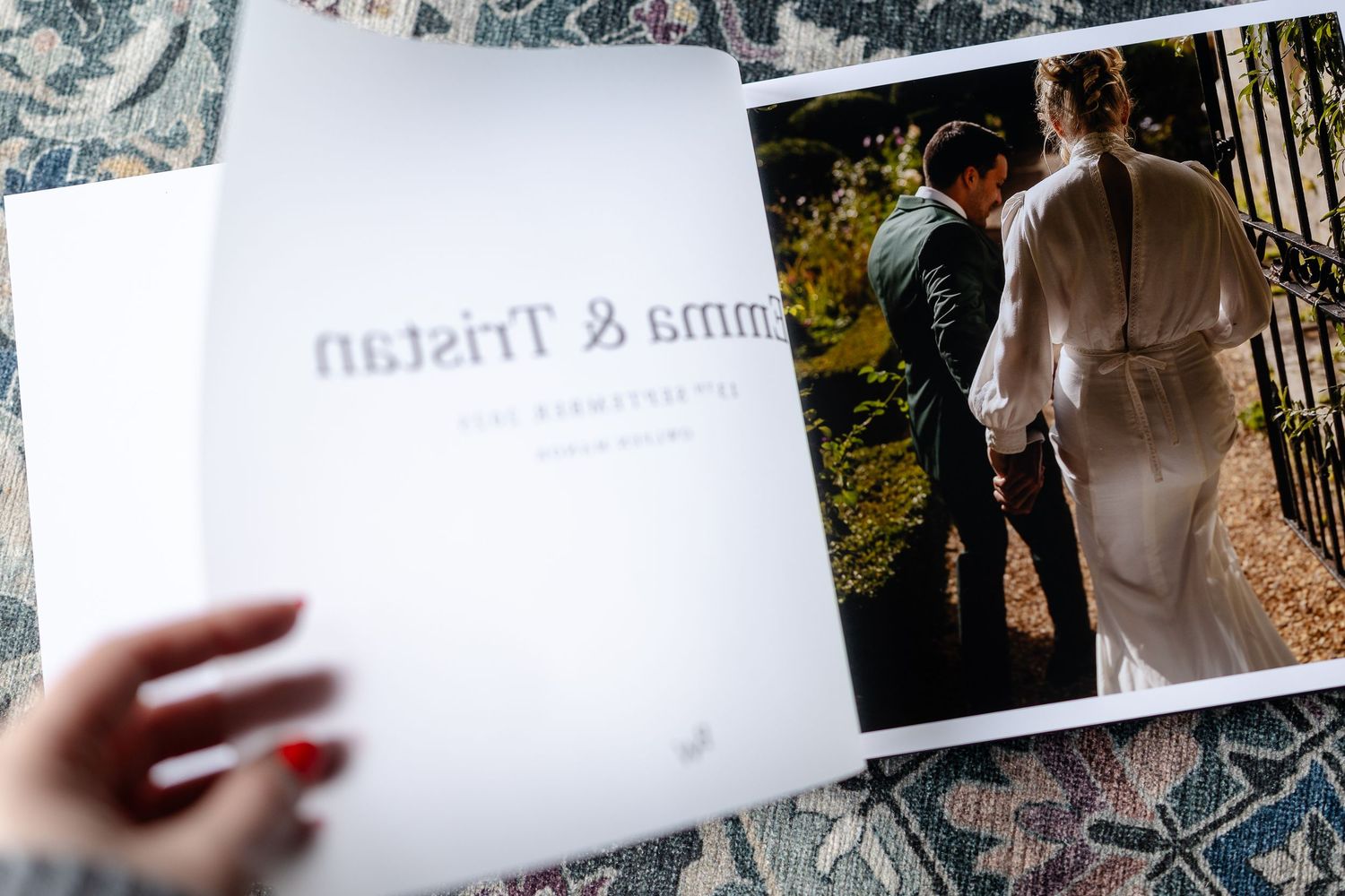 Wedding photo album page showing a couple walking outdoors and white paper with elegant text in the foreground.