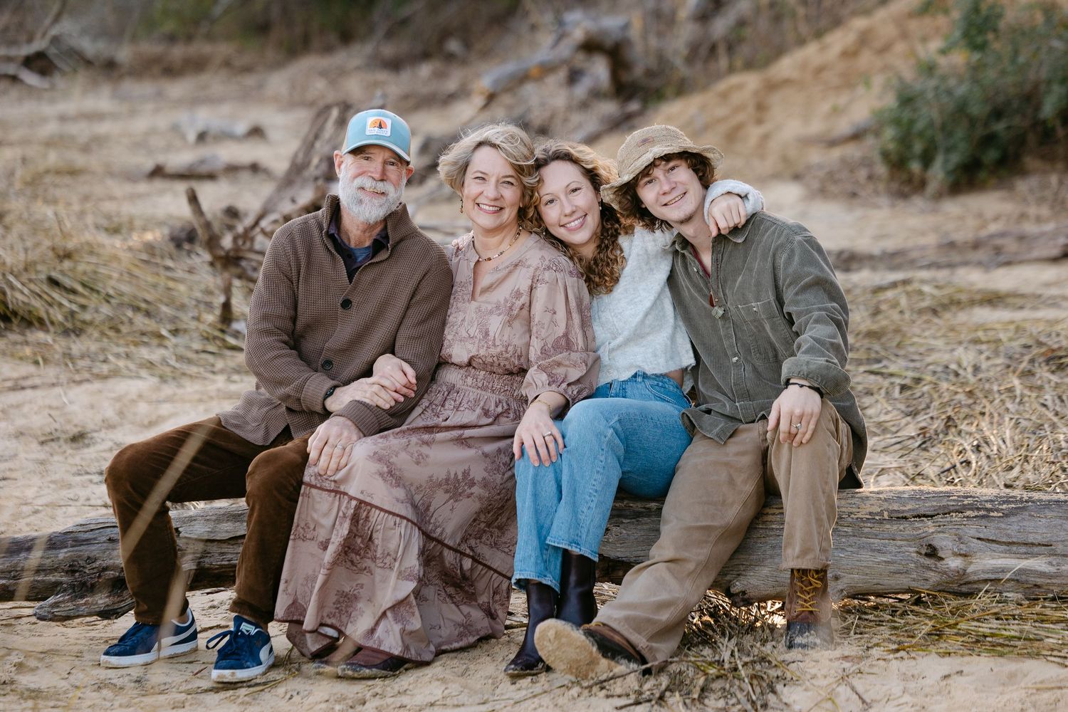 Family enjoying a relaxed outdoor photo session on a rocky hillside during golden hour.