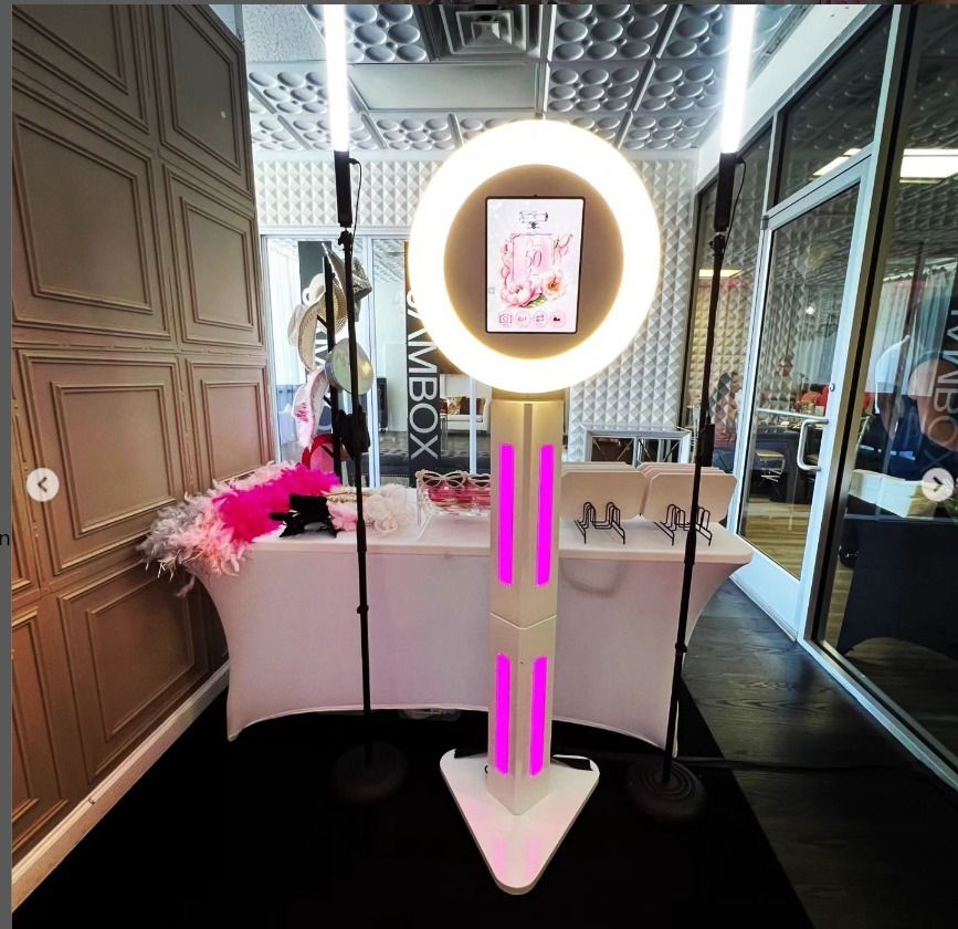 Modern beauty studio interior with pink decor and illuminated ring light stand displaying artwork.
