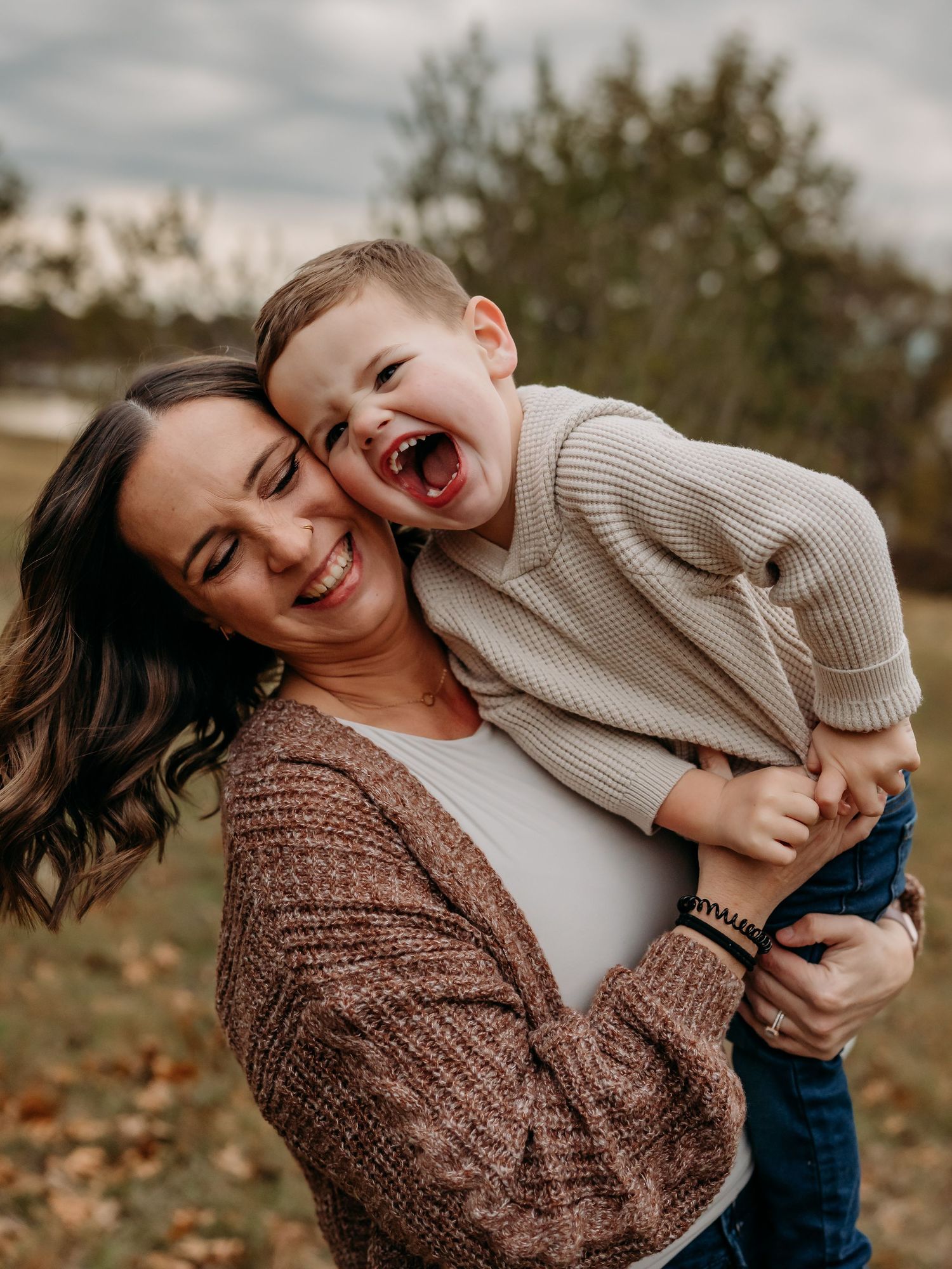 A joyful candid moment captured outdoors on an autumn day with warm sweaters and natural expressions.