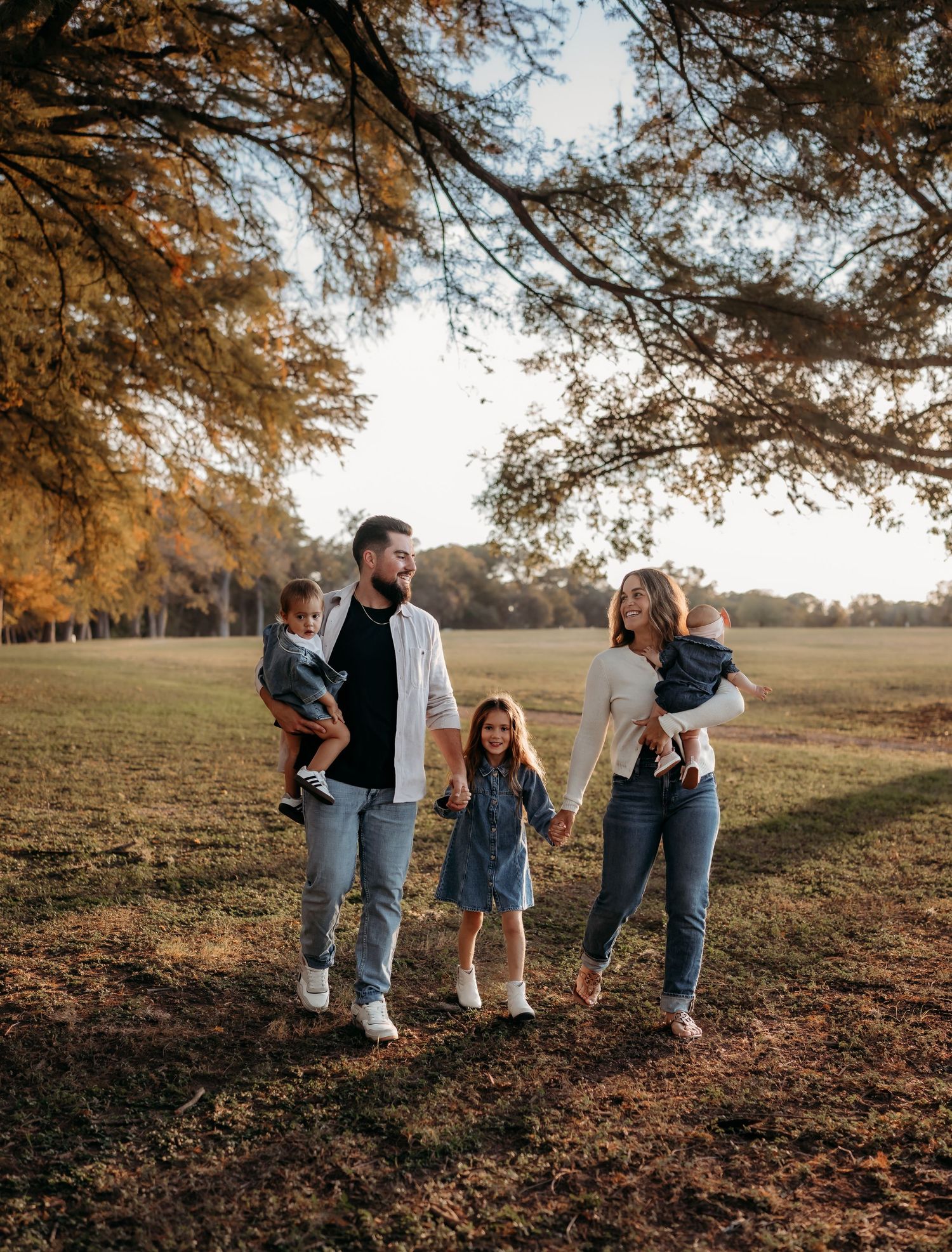 A family shares playful moments together in a golden autumn field during sunset.