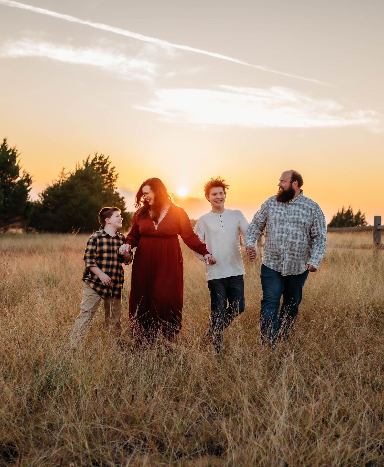 A group walks together through a golden wheat field at sunset casting long shadows across the landscape.