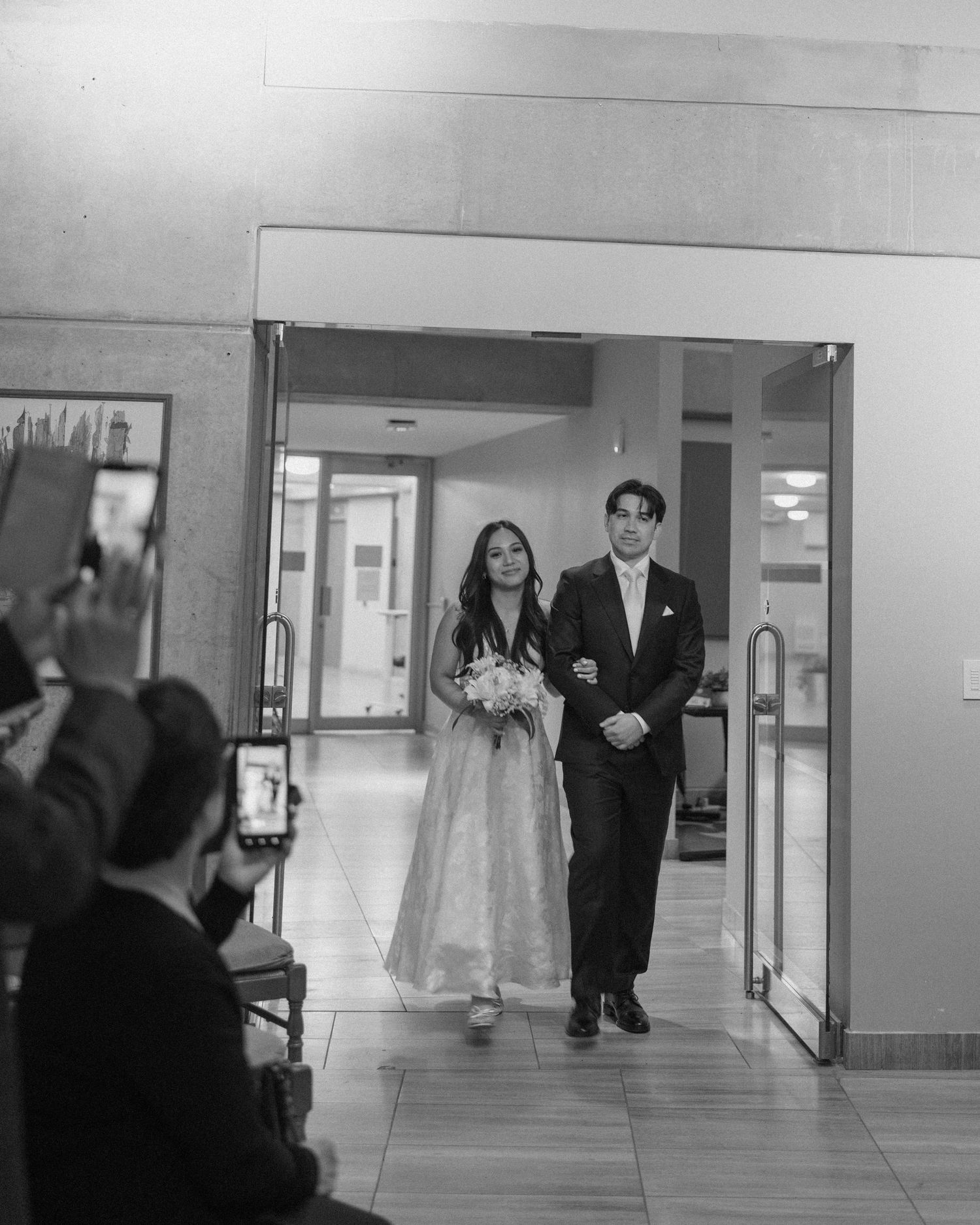Black and white photo of a bride and groom making their grand entrance at their wedding reception.