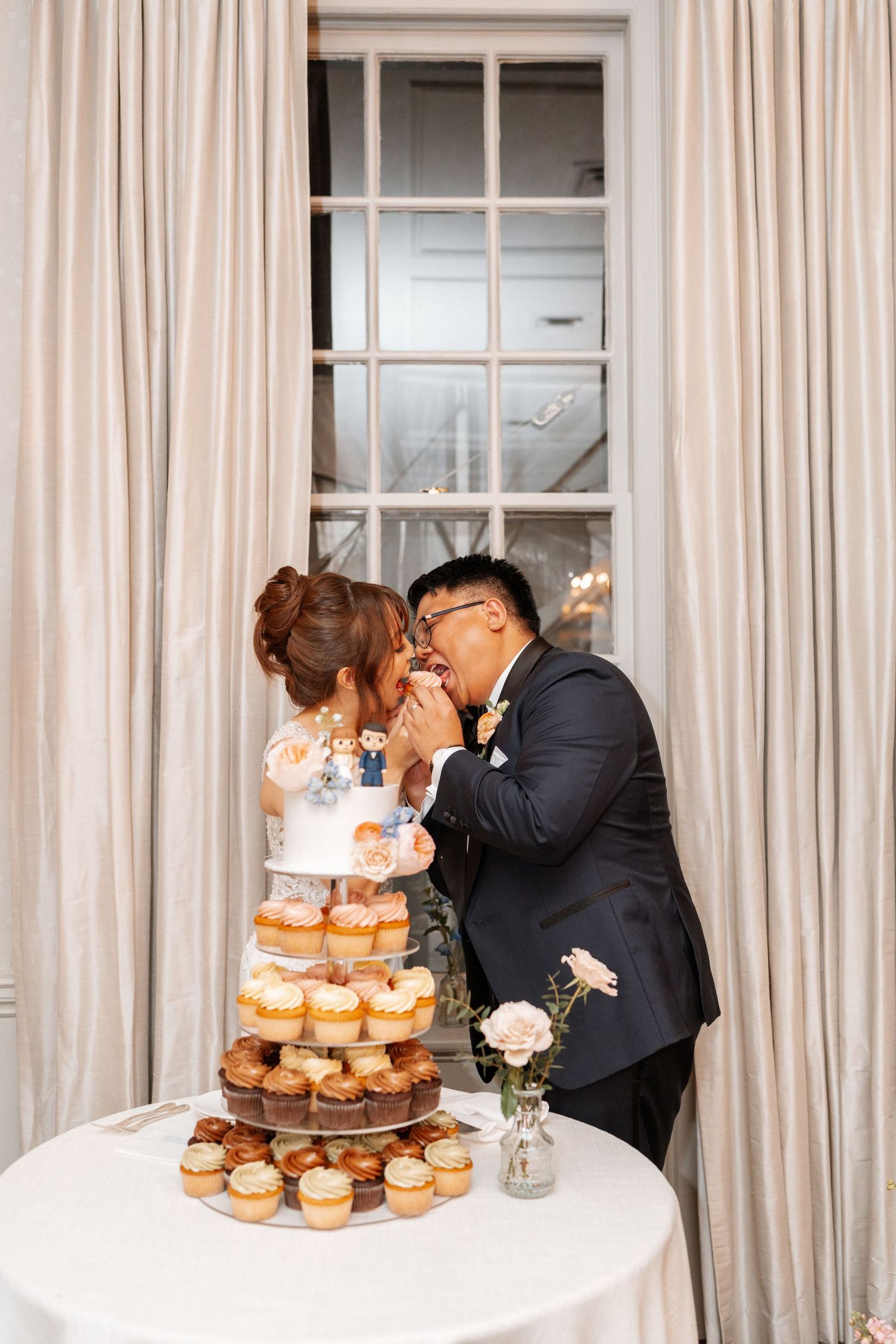 Couple sharing donuts from their tiered wedding donut tower at an elegant reception venue.