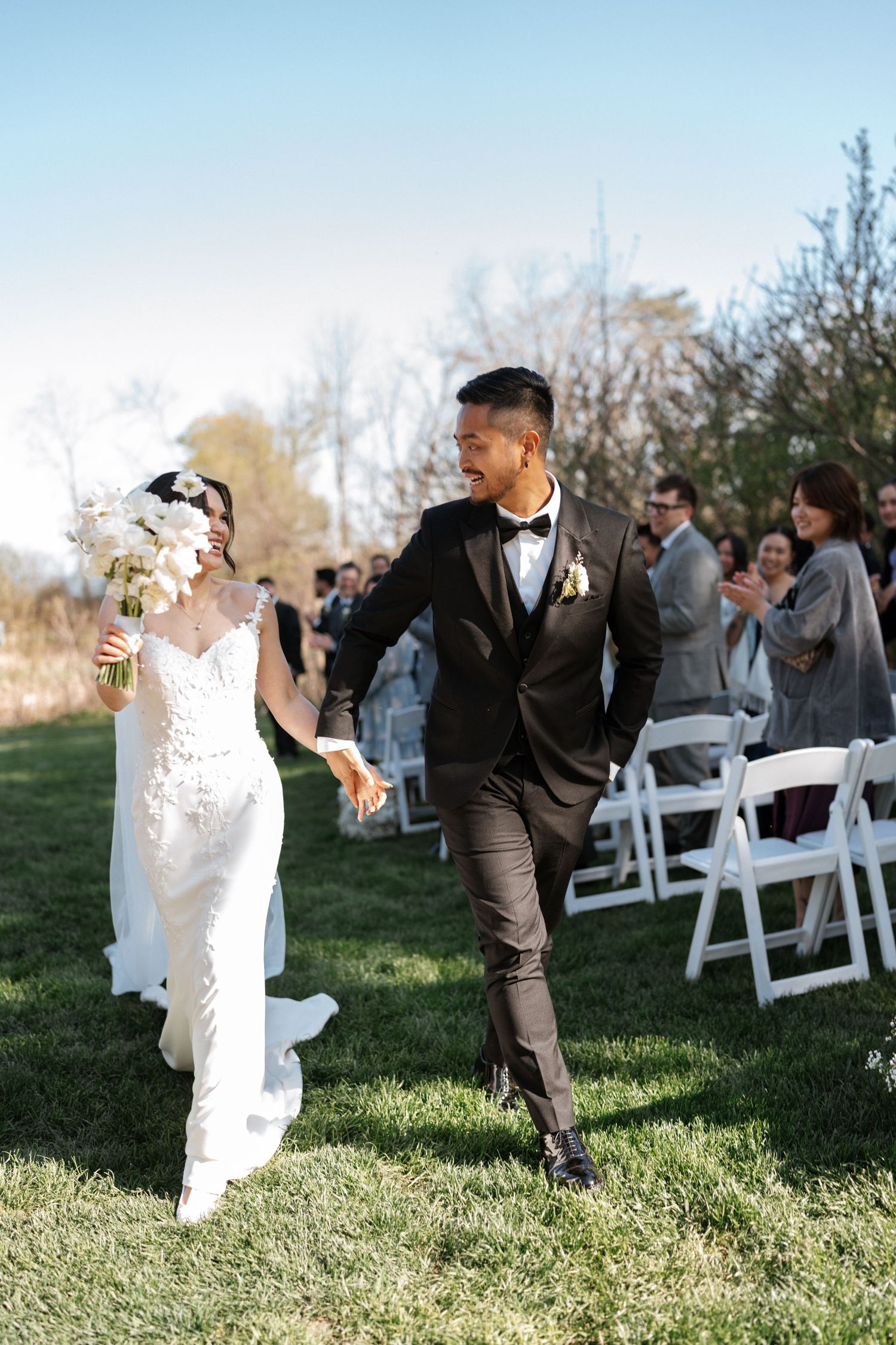 Newlyweds celebrate while walking down the aisle at an outdoor garden wedding ceremony.