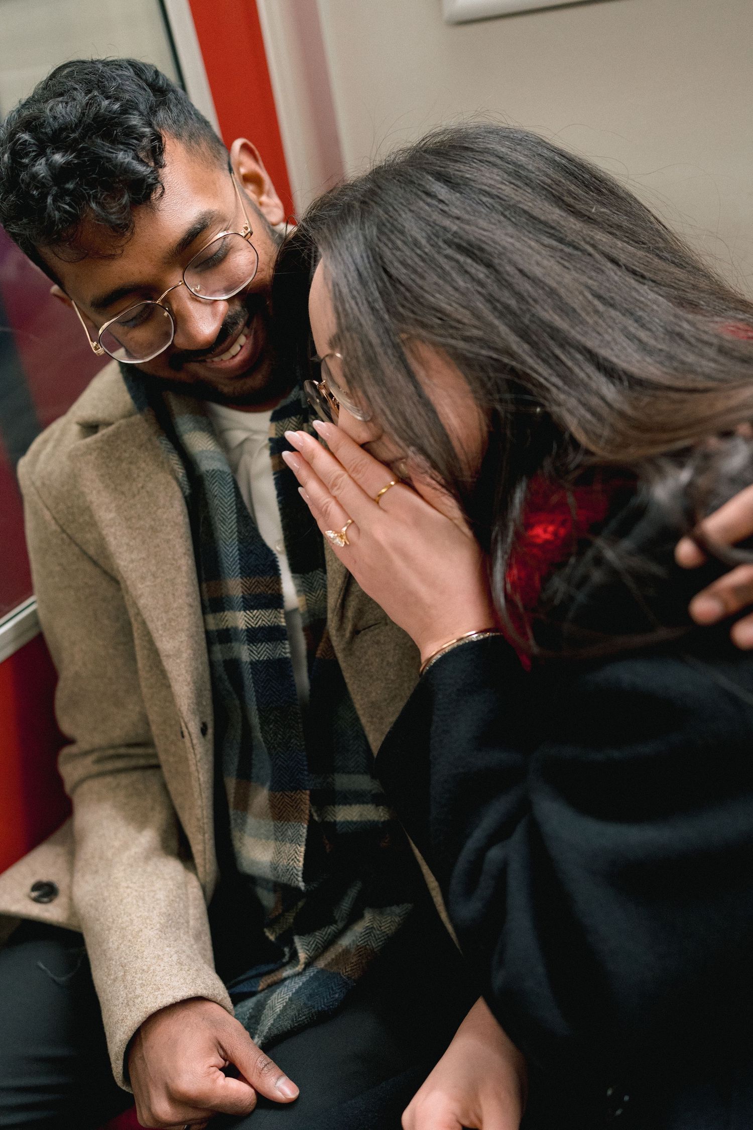 A couple shares an intimate laughing moment together while sitting close on a couch.