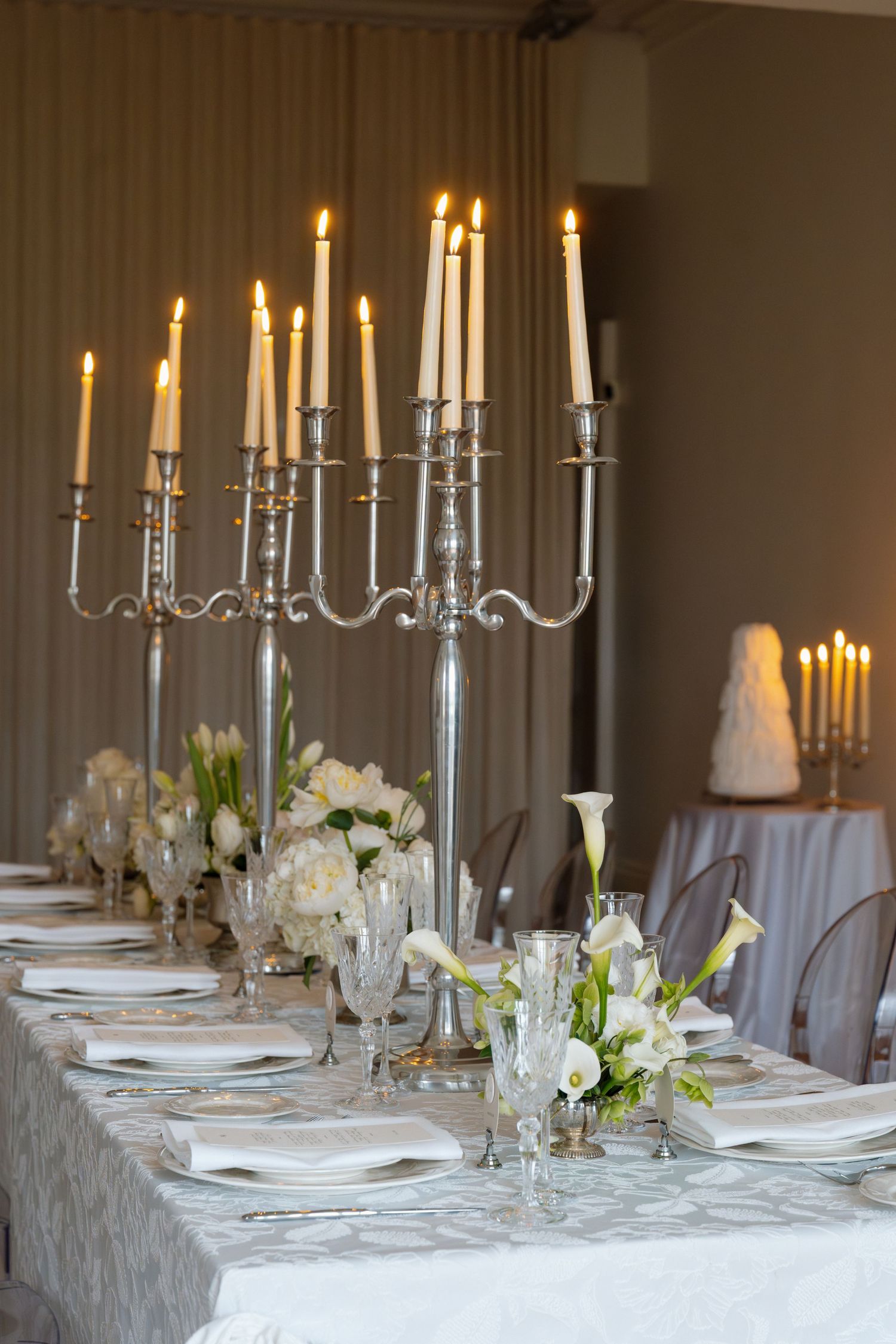 Formal wedding reception table set with silver candelabras, white florals, crystal glassware and fine china.