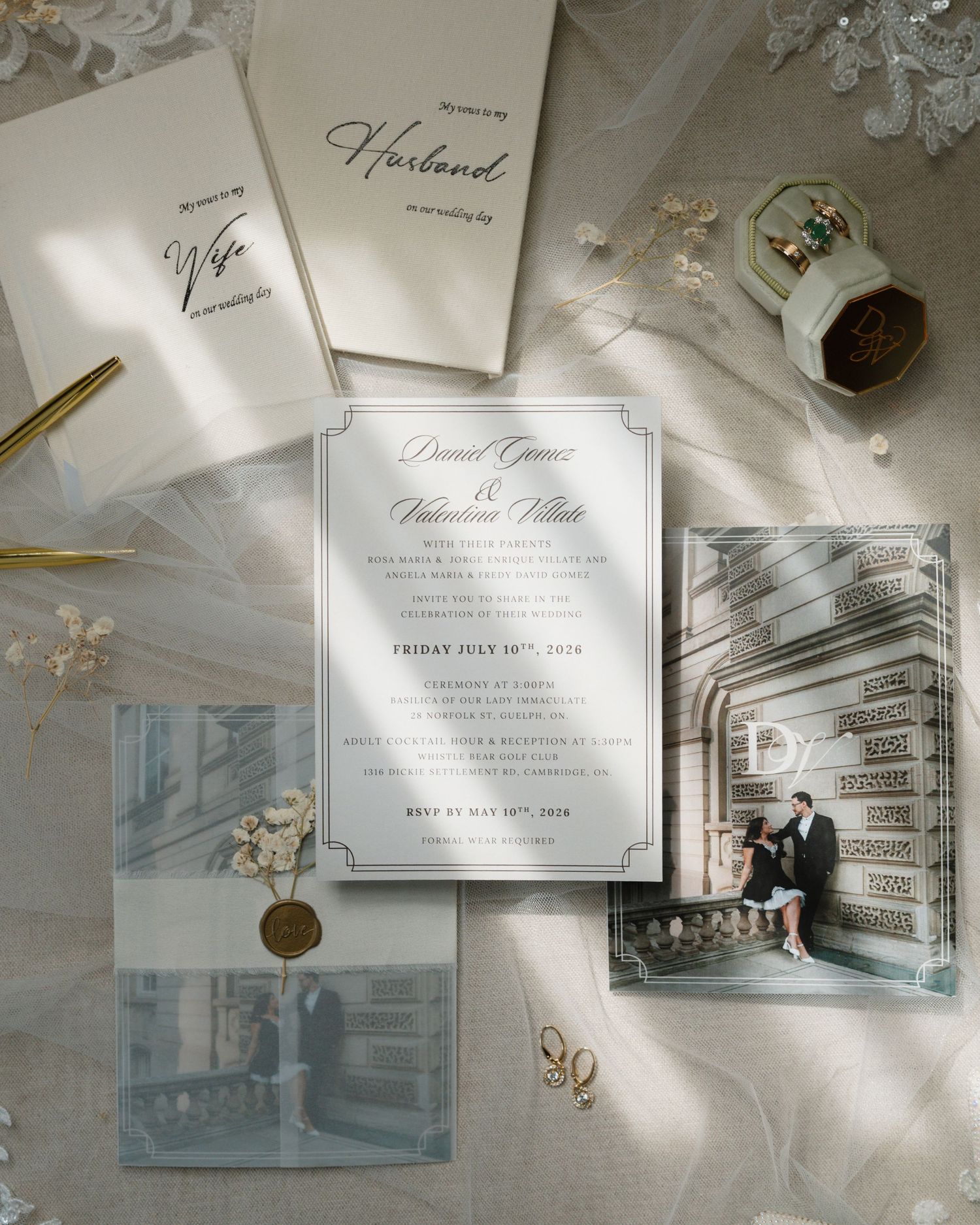 Elegant wedding invitation suite with vellum envelope, photo print, and calligraphy cards on a soft draped fabric background.