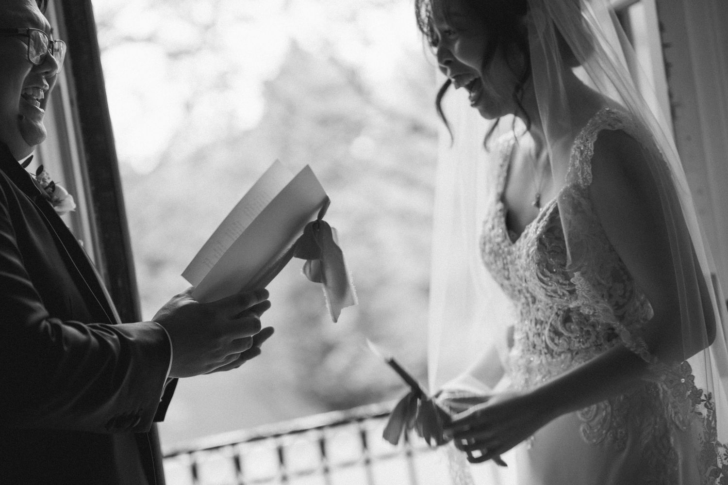 Black and white photo of bride and guest exchanging letters on wedding day.