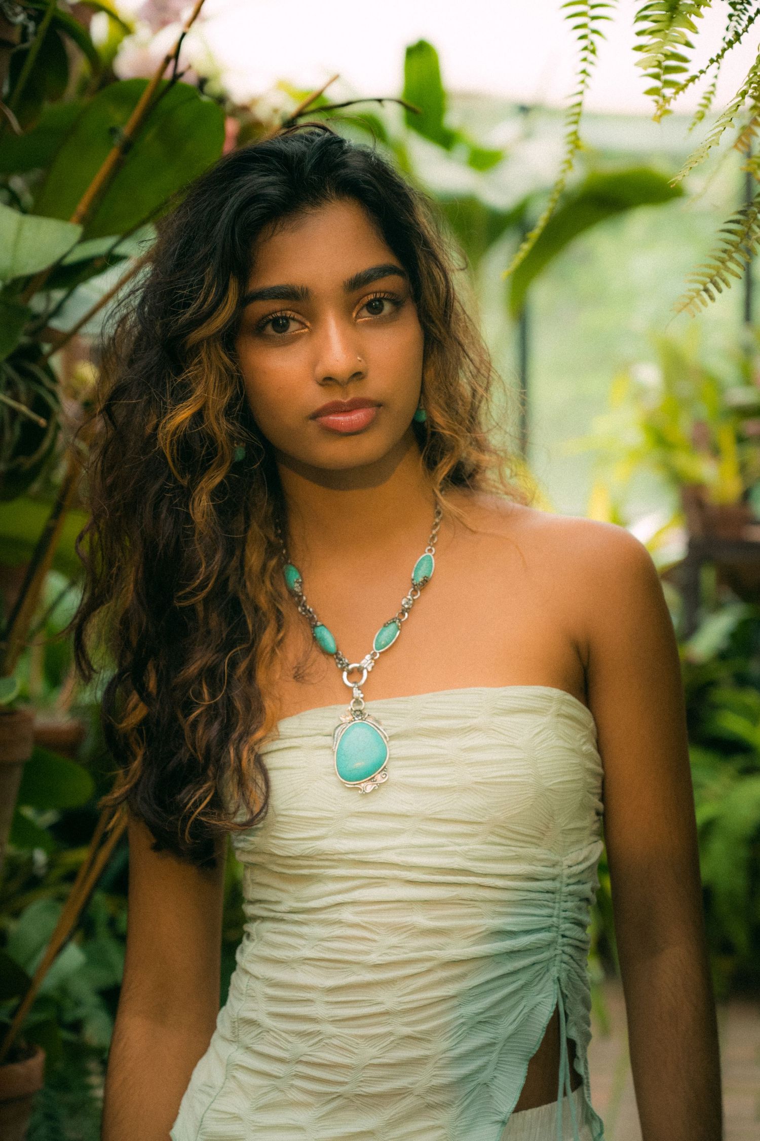 Portrait in natural light with tropical foliage background and turquoise statement necklace.