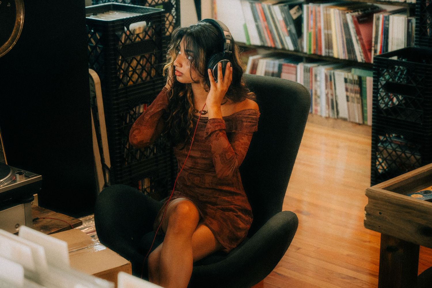 Person in red dress sitting in a reading nook with bookshelves in the background.