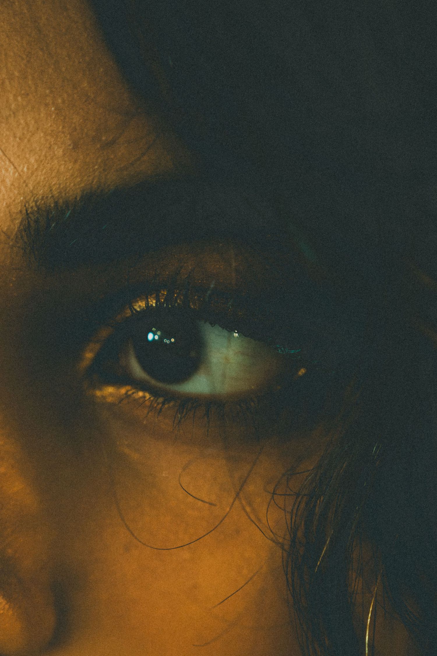 Close-up artistic shot of an eye illuminated by warm golden light.