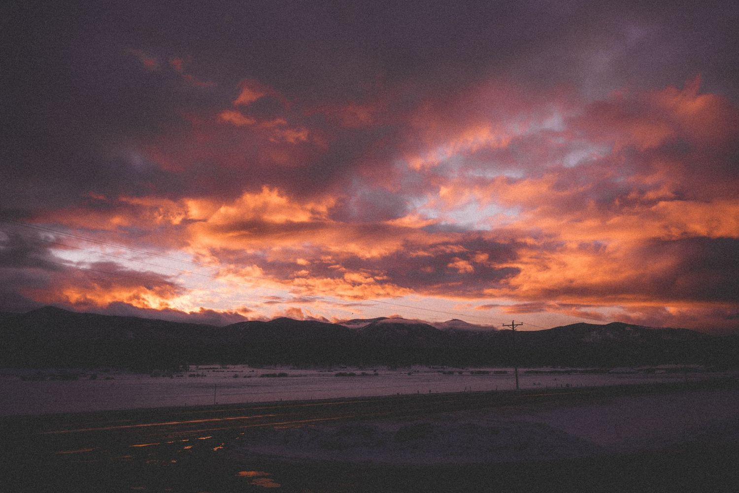 Dramatic purple and orange sunset clouds over dark mountain silhouettes.