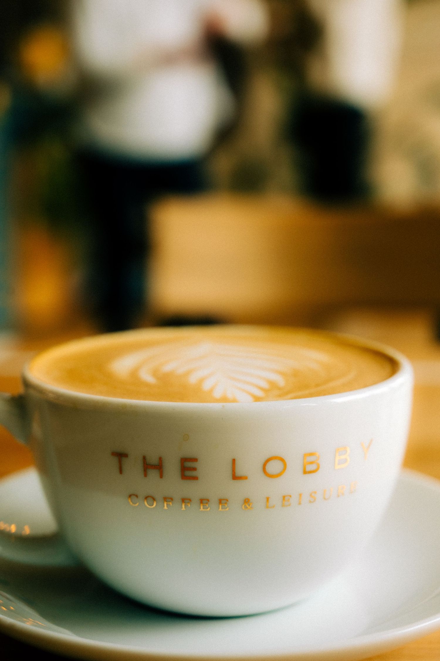 Artistically shot latte art in white ceramic cups with 'THE LOBBY' branding visible.