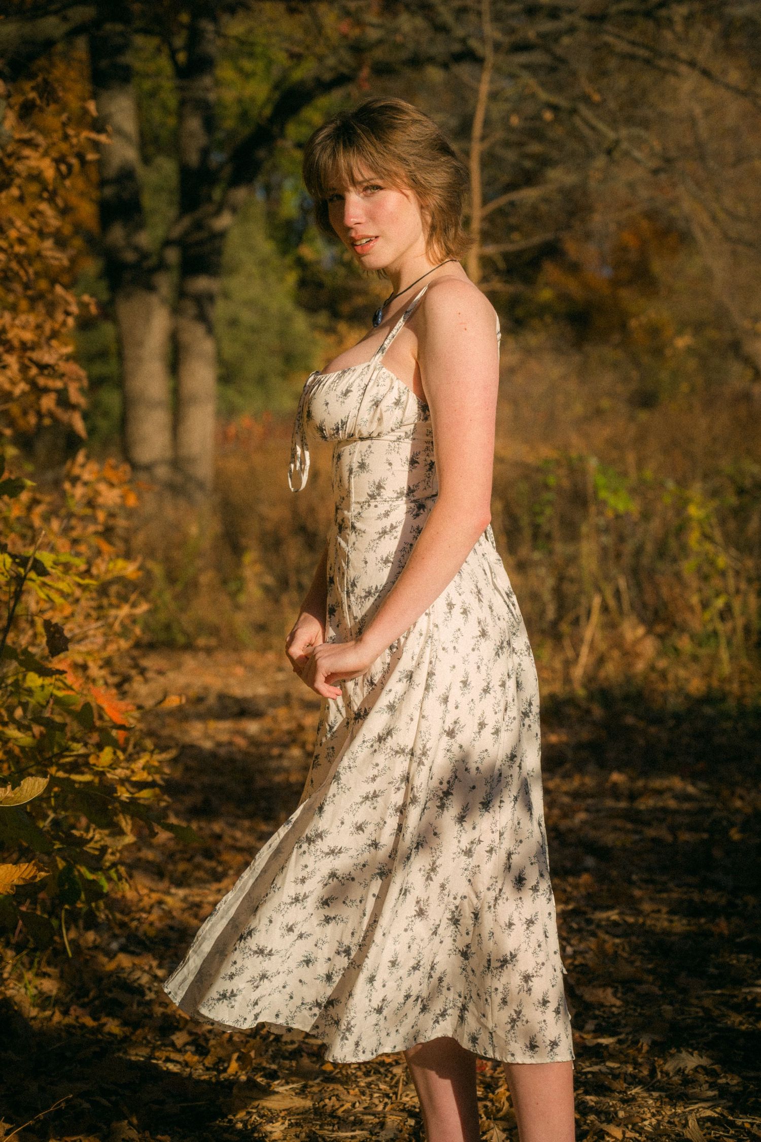 A flowing white dress captured in motion against a golden autumn forest setting.
